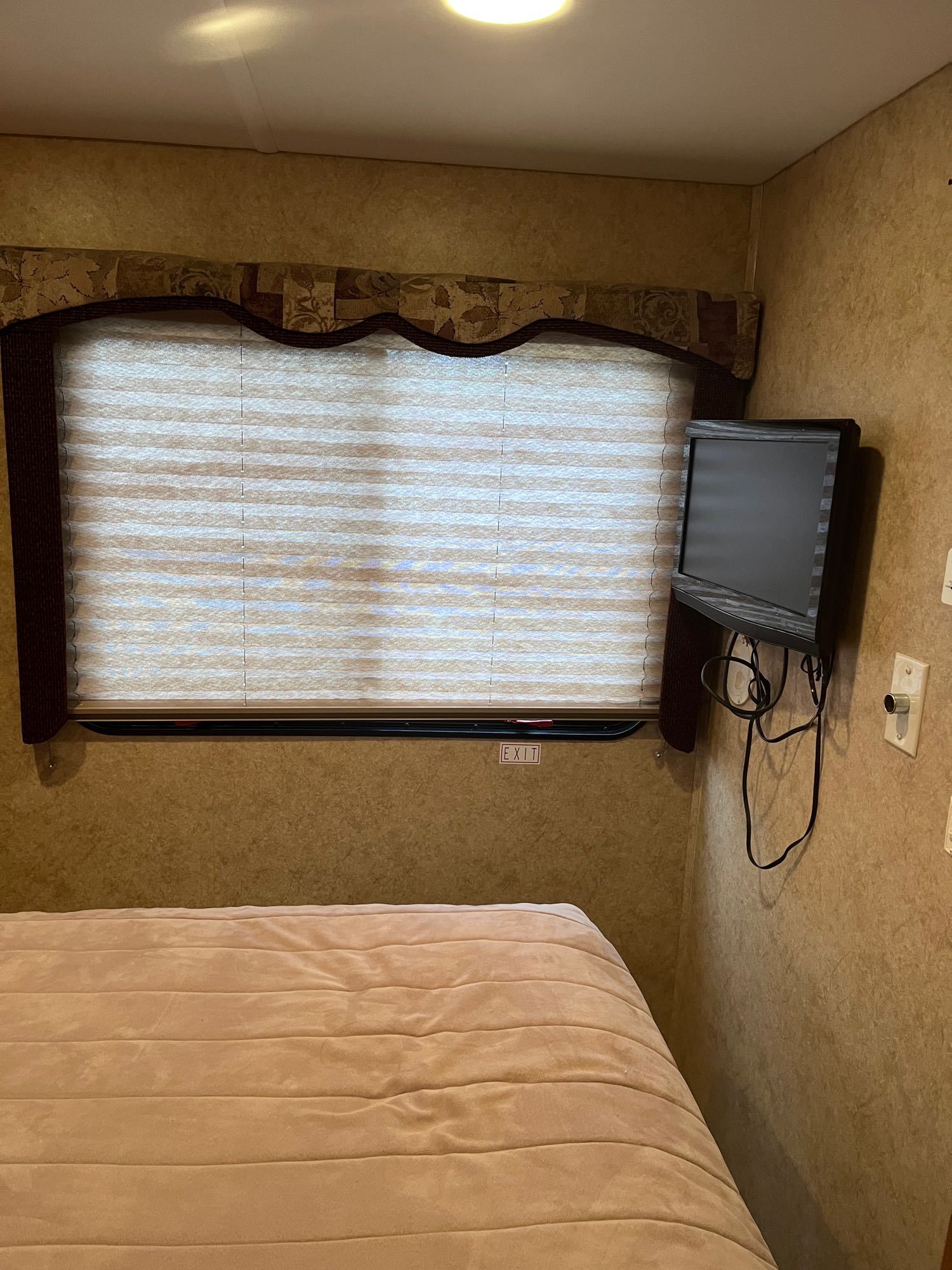 RV rental bedroom with a comfy bed, window, and small TV. Features an EXIT sign for safety and convenience.. Forester Forester Motorhome 2011