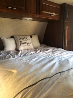 Comfortable RV rental bedroom: A spacious bed with light bedding, pillows, & overhead cabinets. Ready for your adventure.. Keystone Fuzion 2014