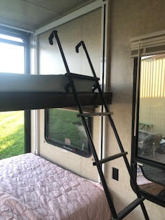 Inside an RV rental: a black ladder leads to an upper bunk bed over a lower bed. Ideal sleeping area for families.. Keystone Fuzion 2014