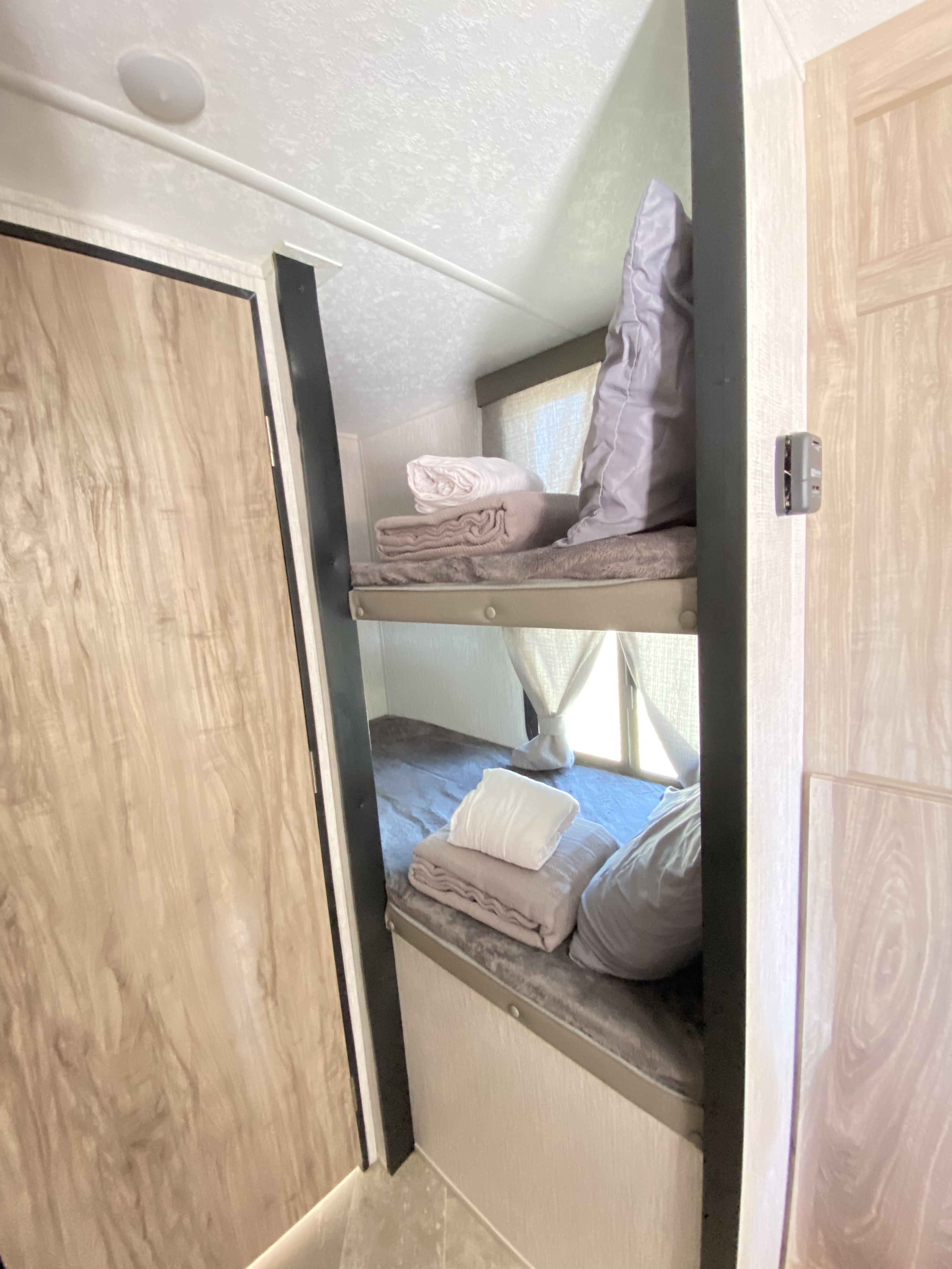 An RV rental interior showing two bunk beds with soft bedding and curtains, offering compact sleeping.. Palomino Other 2022
