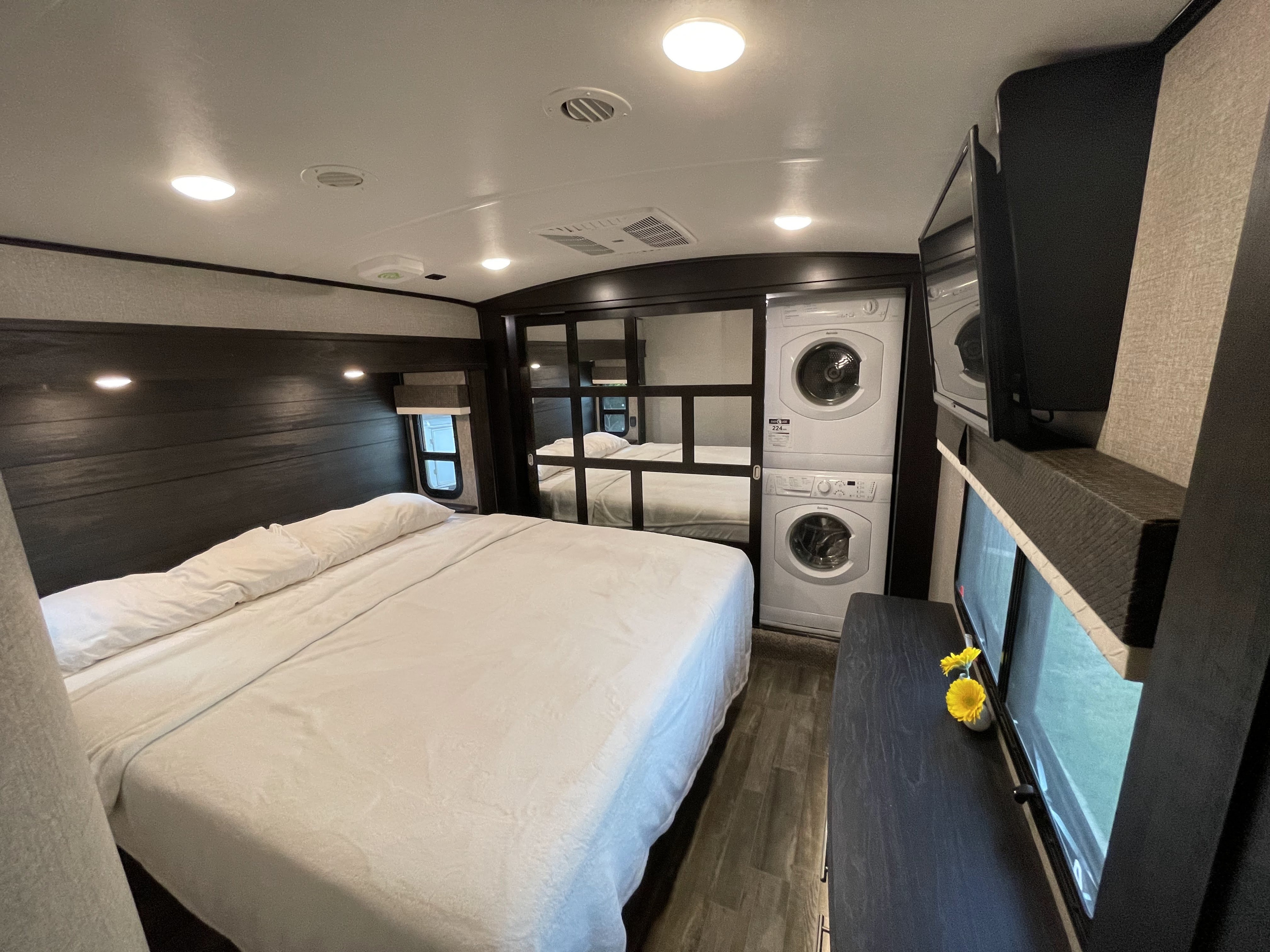 RV rental bedroom with comfy bed, stacked washer/dryer, TV, and mirrored closet, offering full amenities.. Jayco North Point 2020