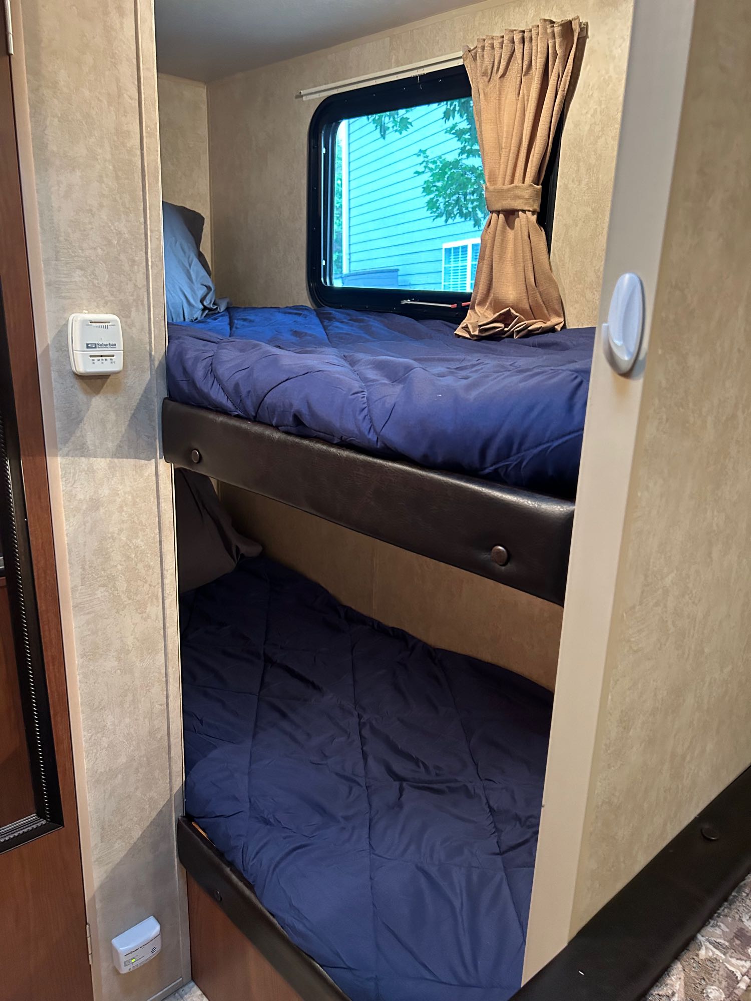 Cozy RV rental bunk beds with blue bedding, a window, and climate control, offering a comfortable sleeping area inside.. Forest River Wildwood X-Lite FS 2014
