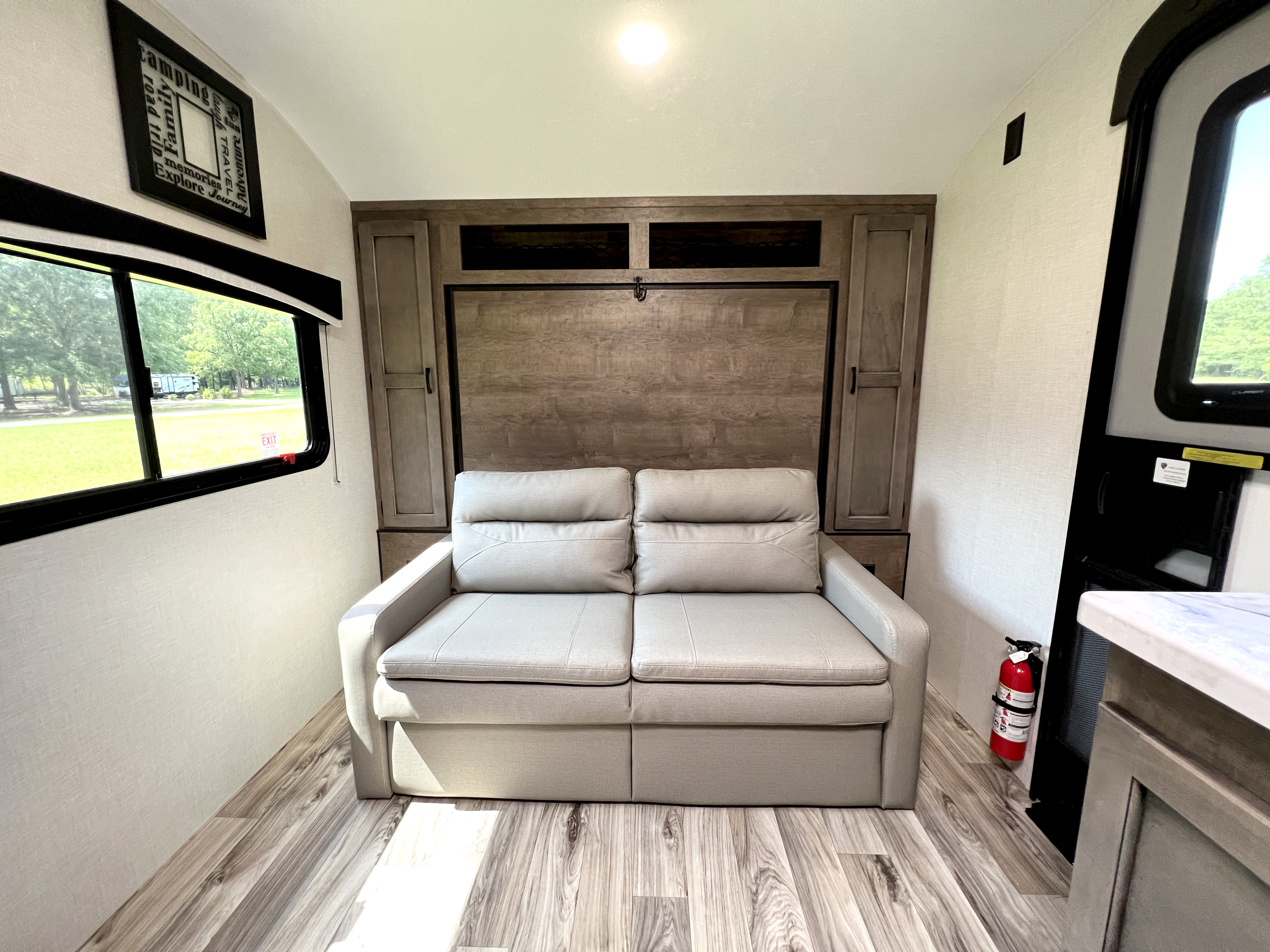 Spacious rv rental interior with a comfortable sofa, convertible bed, window view, and wood floors, ideal for camping.. Venture Rv Sonic 2023