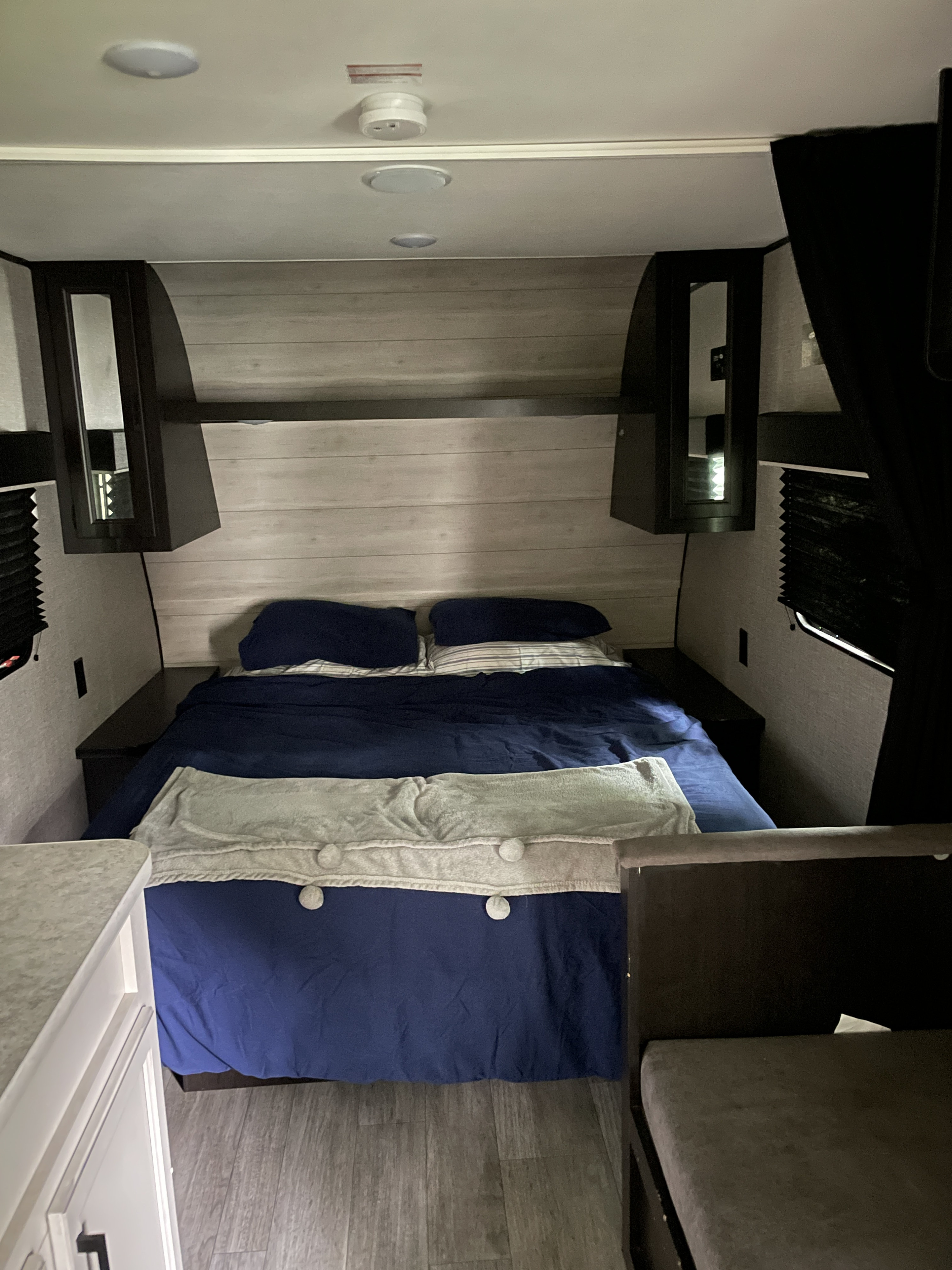 Cozy RV rental bedroom featuring a full bed, overhead storage, and modern wood-panel interior.. Jayco Jay Flight SLX 2022