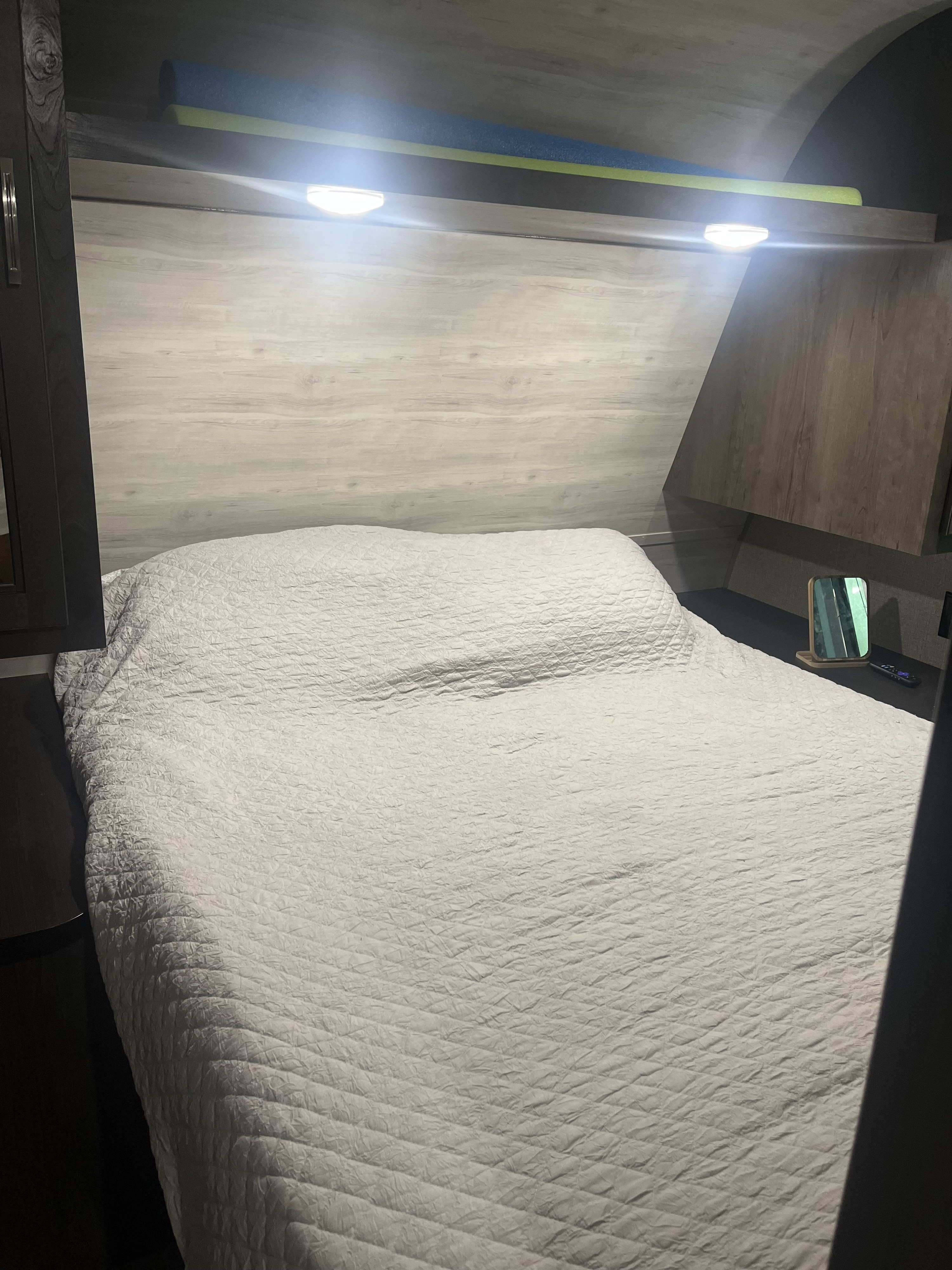 Cozy rv rental bedroom. Features a comfortable bed with quilted cover, bright overhead lights, and storage space.. Jayco Jay Flight SLX 2021