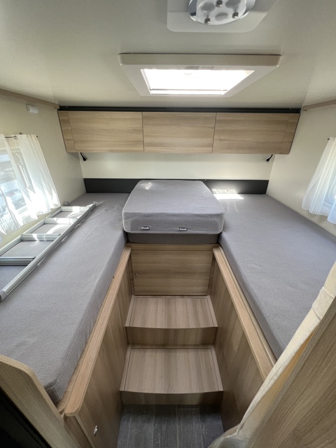 RV rental: Look into the sleeping area with a large raised bed, wooden steps for access, overhead storage, and a bright skylight.. ITINEO PJ 700 2025