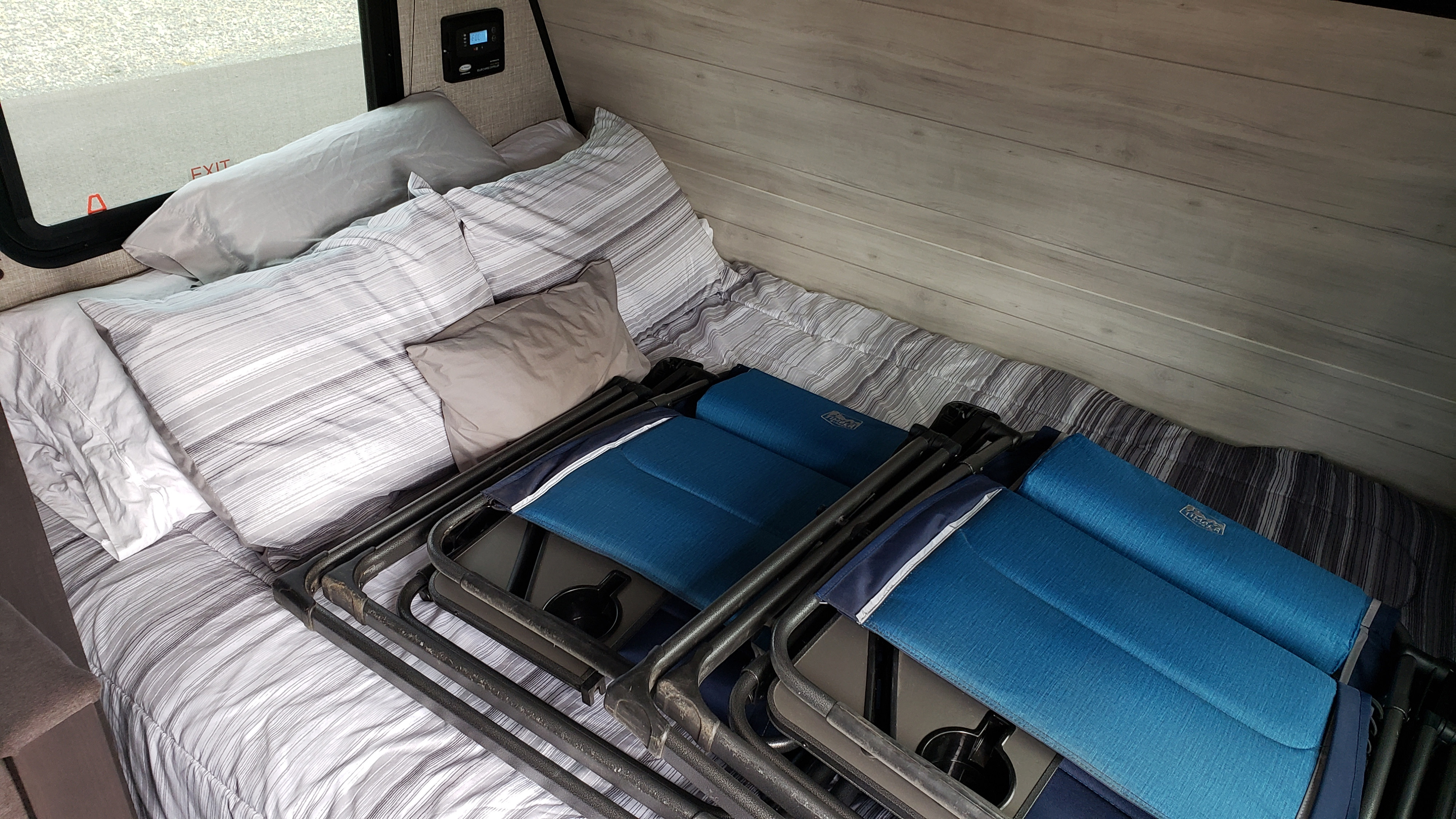 RV rental bedroom featuring a bed with striped linens & folded blue camping chairs, ready for travel.. Jayco Jay Flight SLX Baja Edition 2022