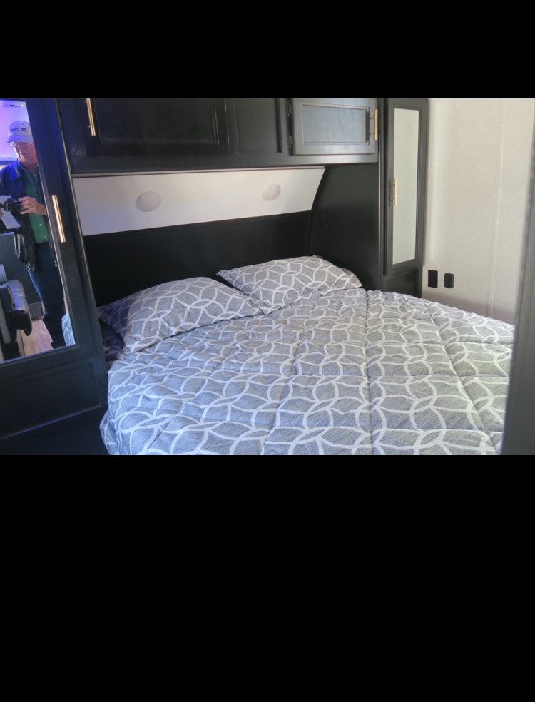 Comfortable RV rental bedroom with patterned bedding, overhead storage, and compact design.. Forest River Cherokee Grey Wolf 2021