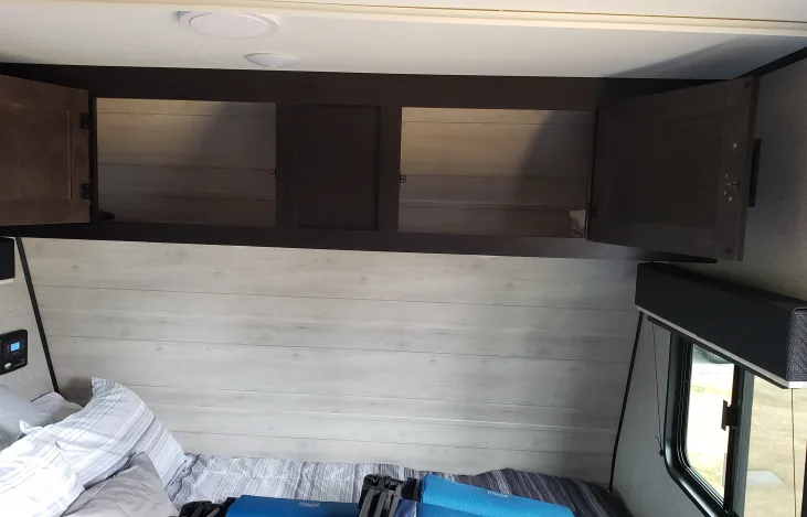 Cozy RV rental bedroom with open overhead storage cabinets, a bed, and compact design for travel.. Jayco Jay Flight SLX Baja Edition 2022