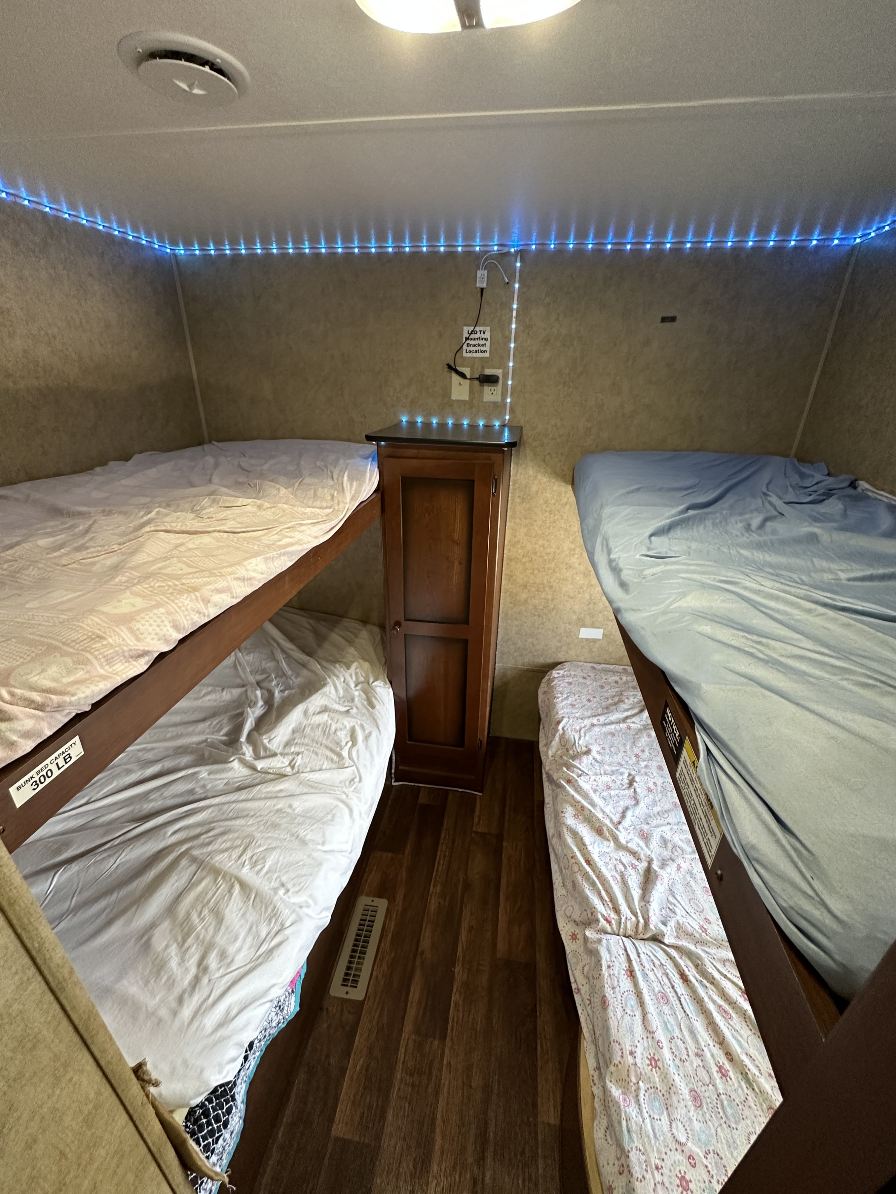 Compact RV rental bunk room with four beds, blue LED lights, and a cabinet for family comfort.. Aspen Trail Aspen Trail Trailer 2013