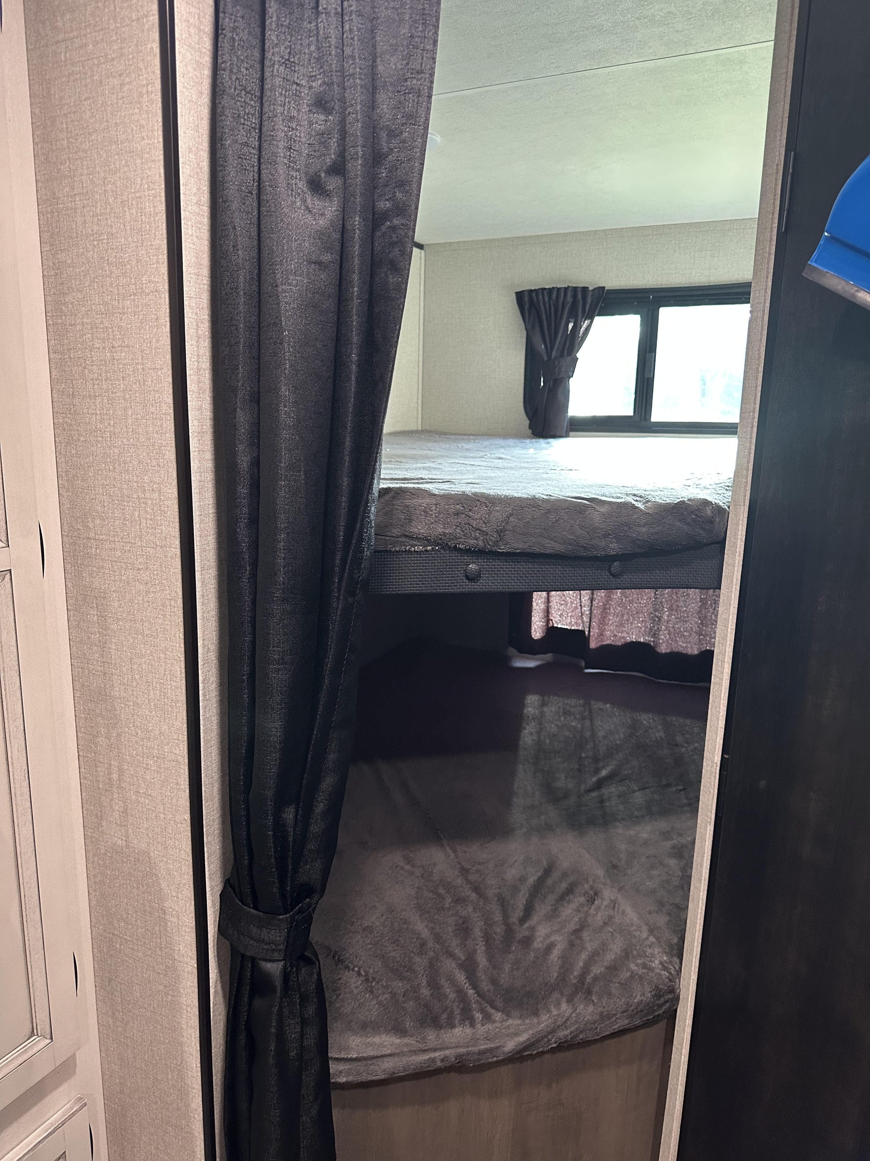 An RV rental features cozy bunk beds with blankets, a window, and privacy curtains, perfect for compact sleeping.. Highland Ridge RV Open Range 2022