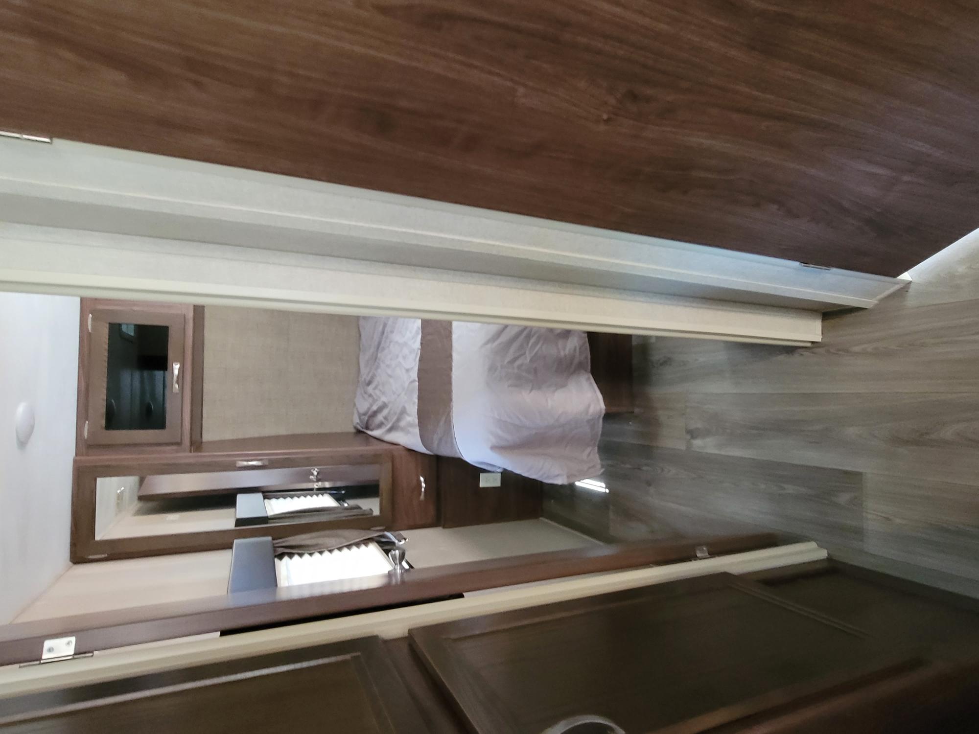 RV rental interior: cozy bedroom with bed & modern compact kitchen/vanity area. Features cabinets, counter, and sink.. Other Other 2018