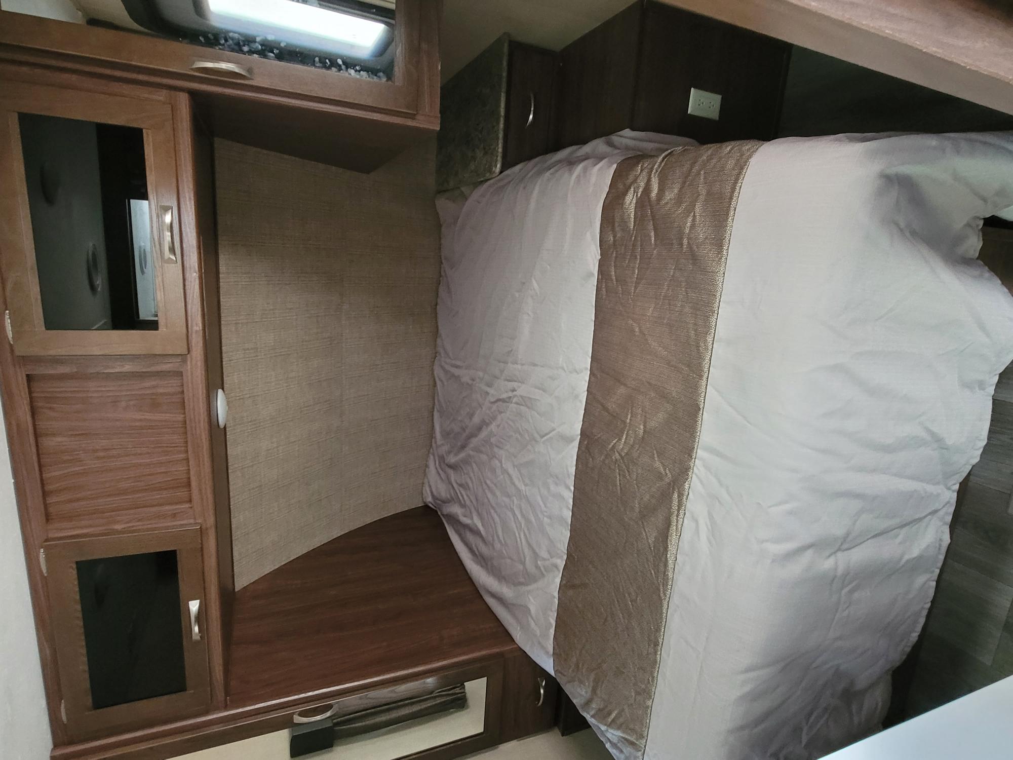 Comfortable RV rental bedroom featuring a cozy bed, built-in wooden cabinets, and an overhead light for travel.. Other Other 2018