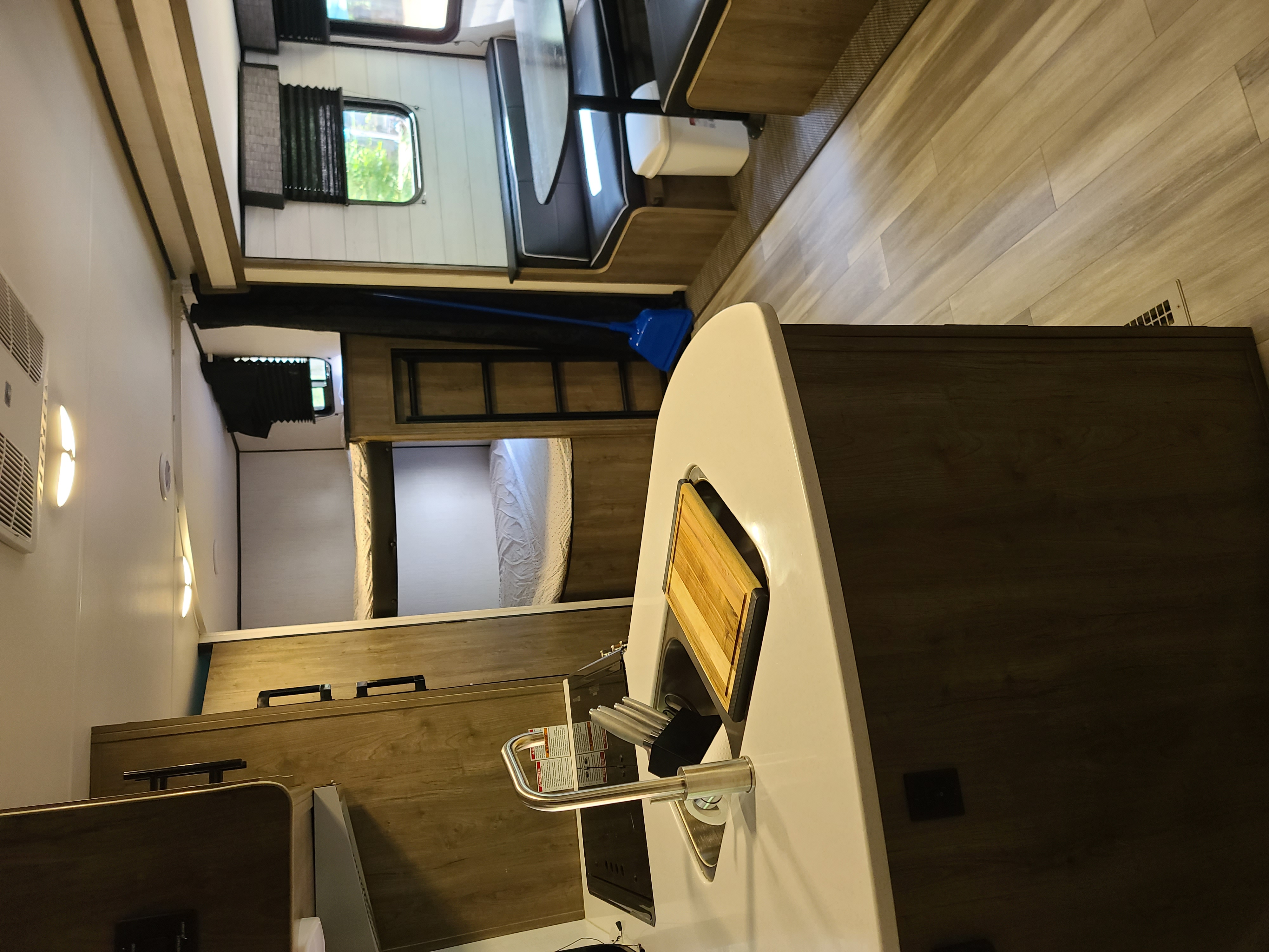 Inside a spacious RV rental: kitchen with cutting board, dining, and cozy bunk beds. Light wood flooring.. Heartland RVs Pioneer bh270 2022