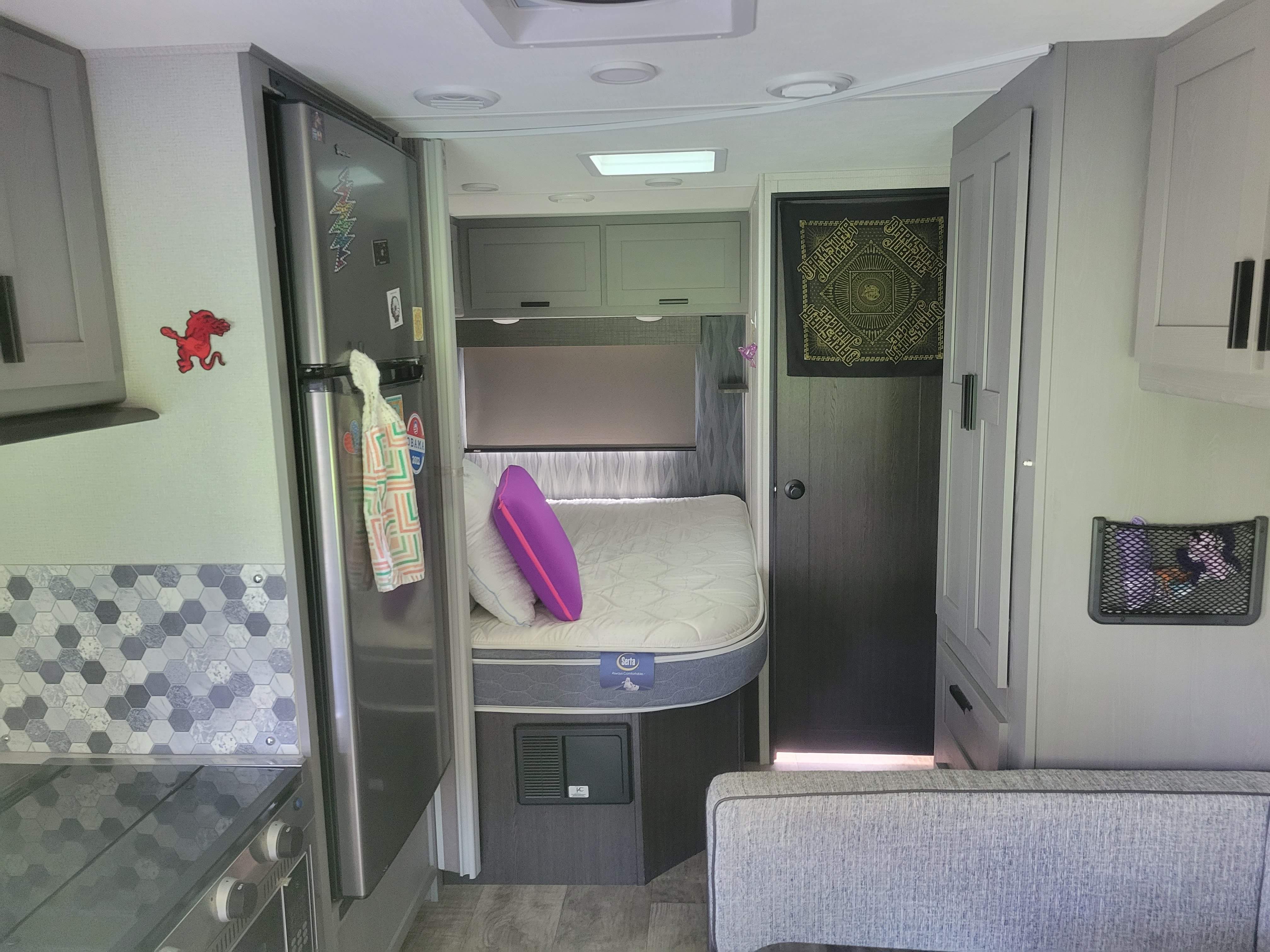 RV rental interior featuring a compact kitchen with fridge, hexagon backsplash, comfortable bed, and storage options.. Solera Solera Motorhome 2022