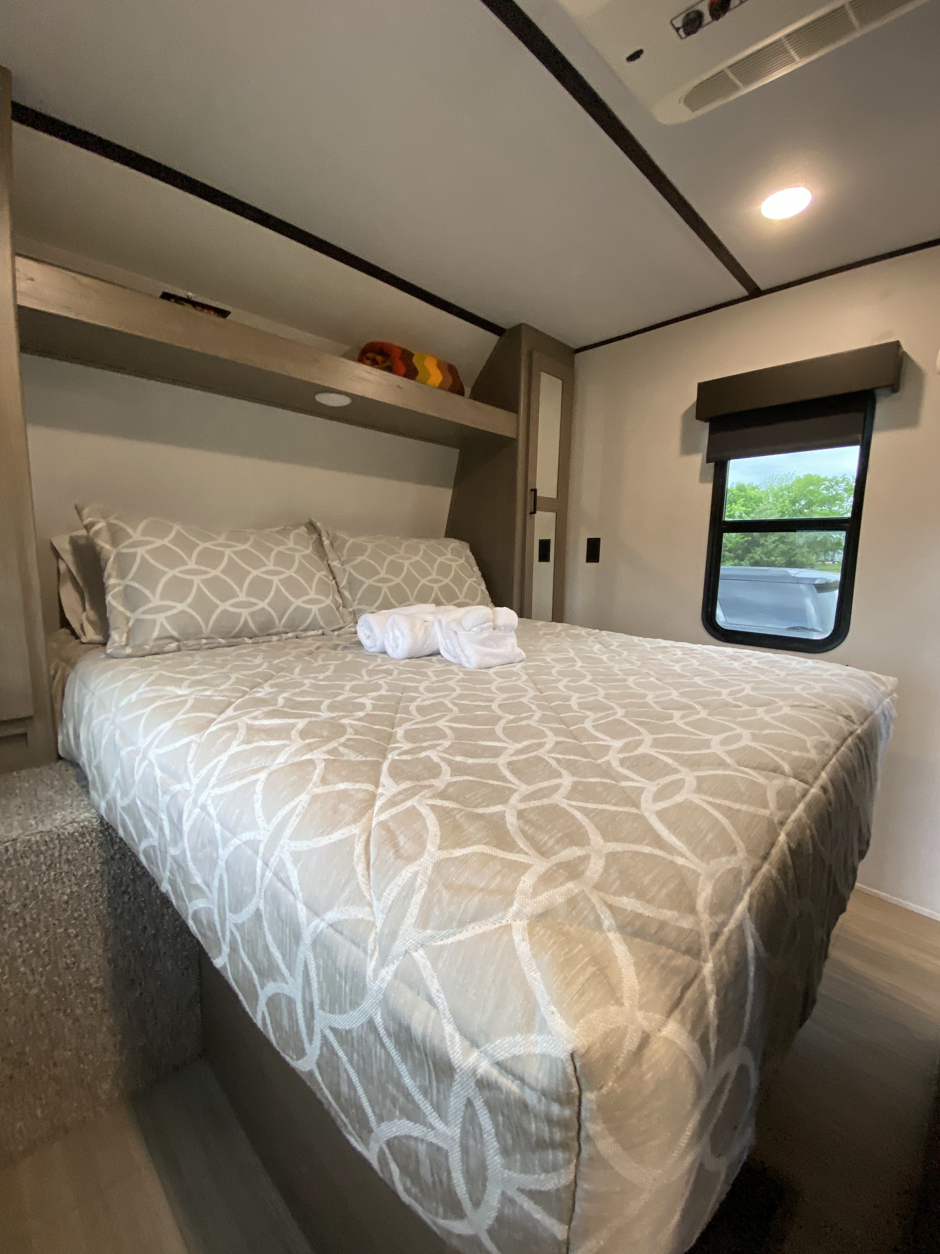 Cozy and comfortable RV rental bedroom featuring a patterned bedspread, pillows, and convenient overhead storage.. Keystone Hideout 2021