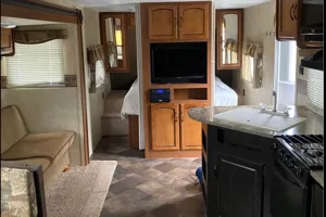 Interior view of an RV rental showing a full kitchen, sofa seating area, and an elevated bedroom. Perfect for travel!. Keystone RV Springdale 2013
