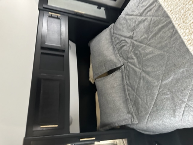 Compact RV rental bedroom with black built-in storage cabinets and cozy grey bedding, optimizing space for travel.. Forest River Cherokee 2022