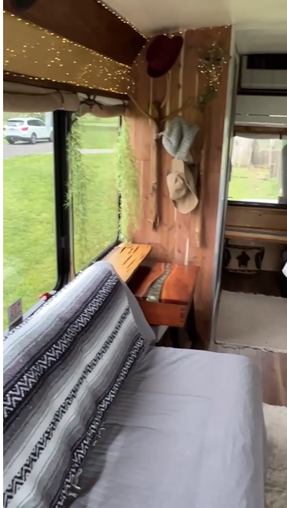 Cozy RV rental interior: rustic wood, string lights, window views, and a comfy bed. Your mobile home awaits!. Ford E-450 2016