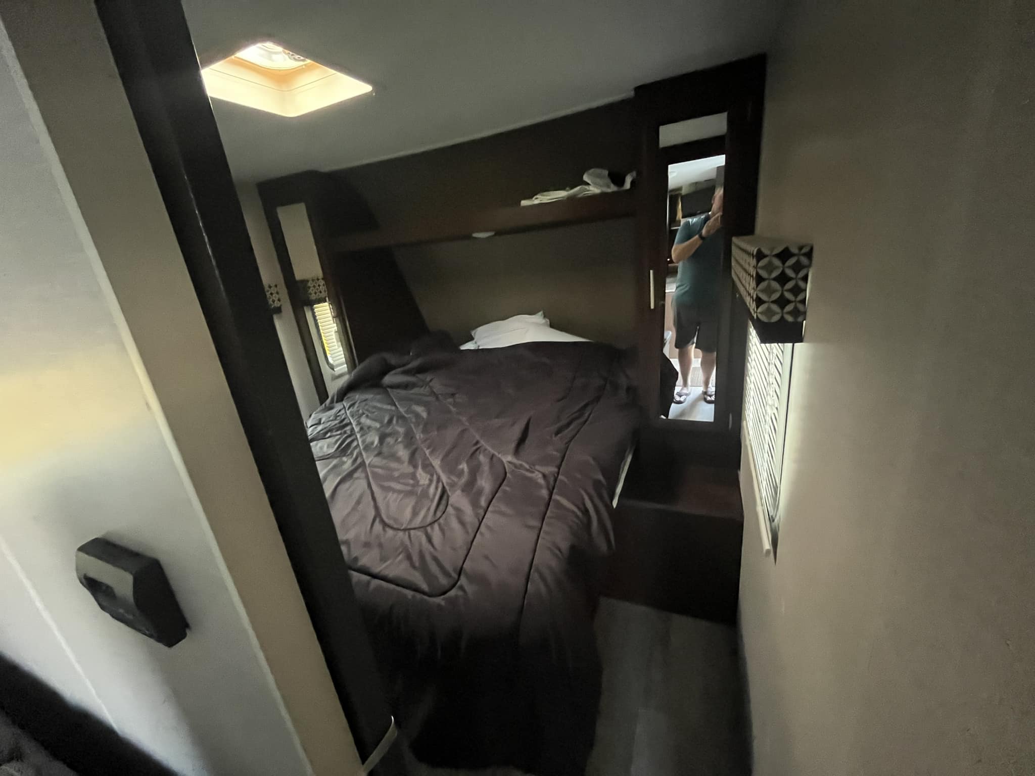 This image captures the compact bedroom of an RV rental, featuring a made bed, skylight, and mirror.. Sportsmen LE 2018