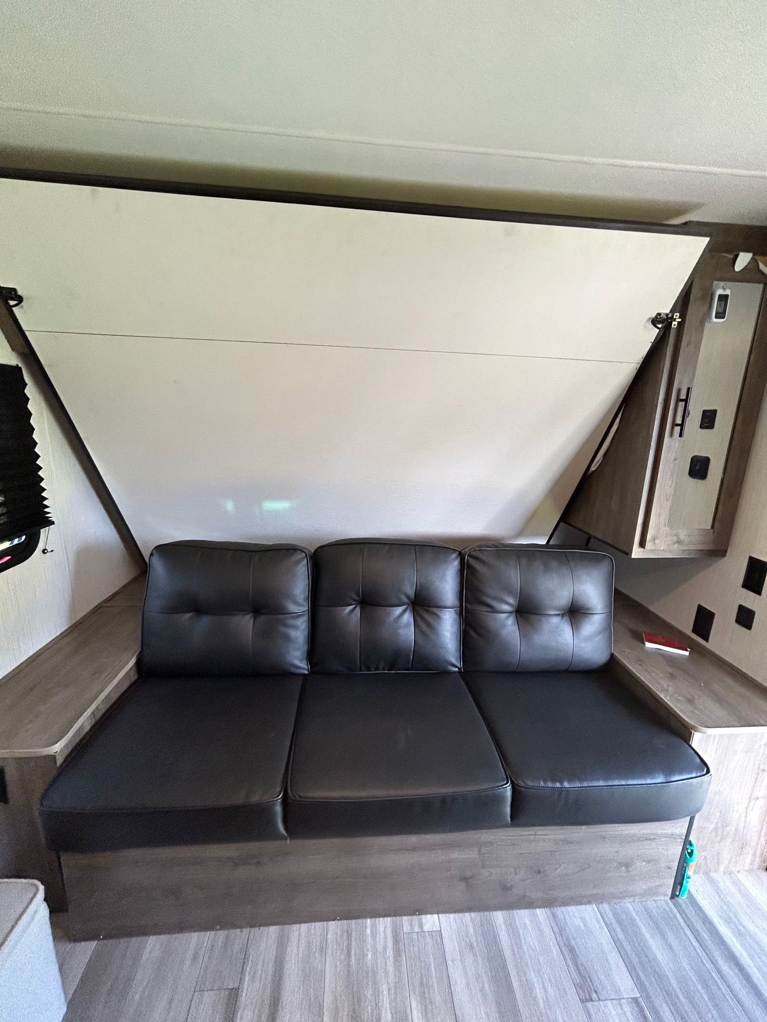 Inside an RV rental: a comfortable black sofa with a partially raised folding bed for versatile living space.. Heartland RVs Pioneer Trail Blazer 2022
