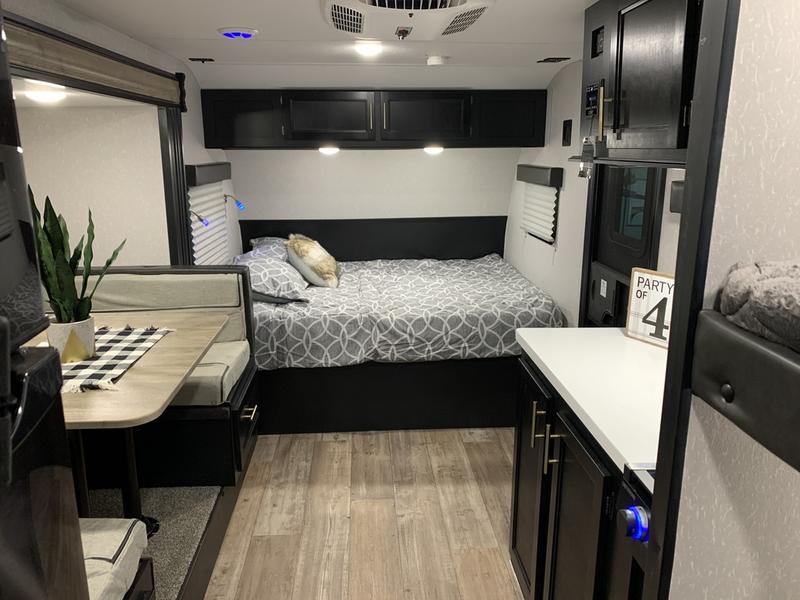 Inside this modern RV rental: a cozy bedroom with patterned bedding, versatile dinette, and compact kitchen space.. Forest River Cherokee Wolf Pup Black Label 2021