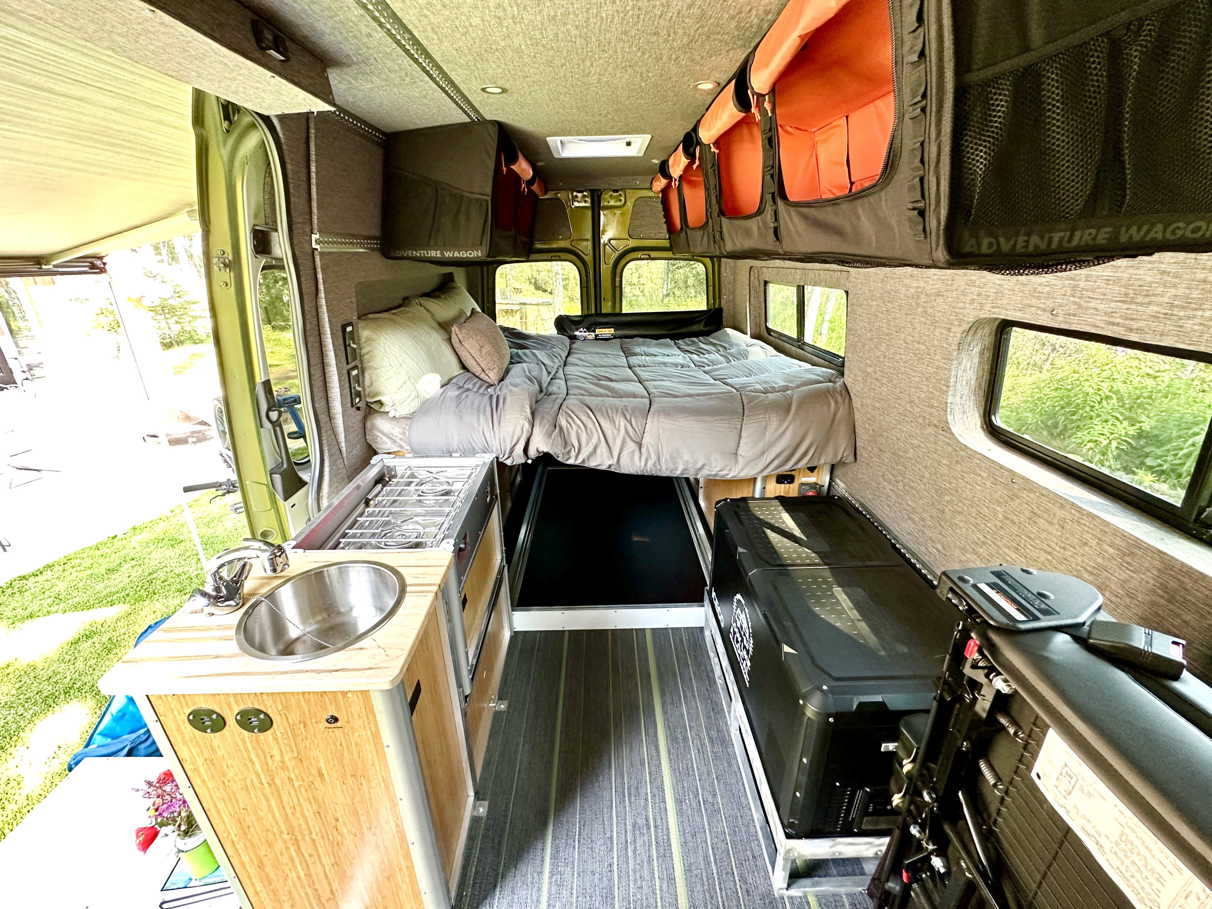 RV rental van interior features a cozy bed, kitchenette with sink/stove, and overhead storage for adventurers.. Freightliner Sprinter 2019