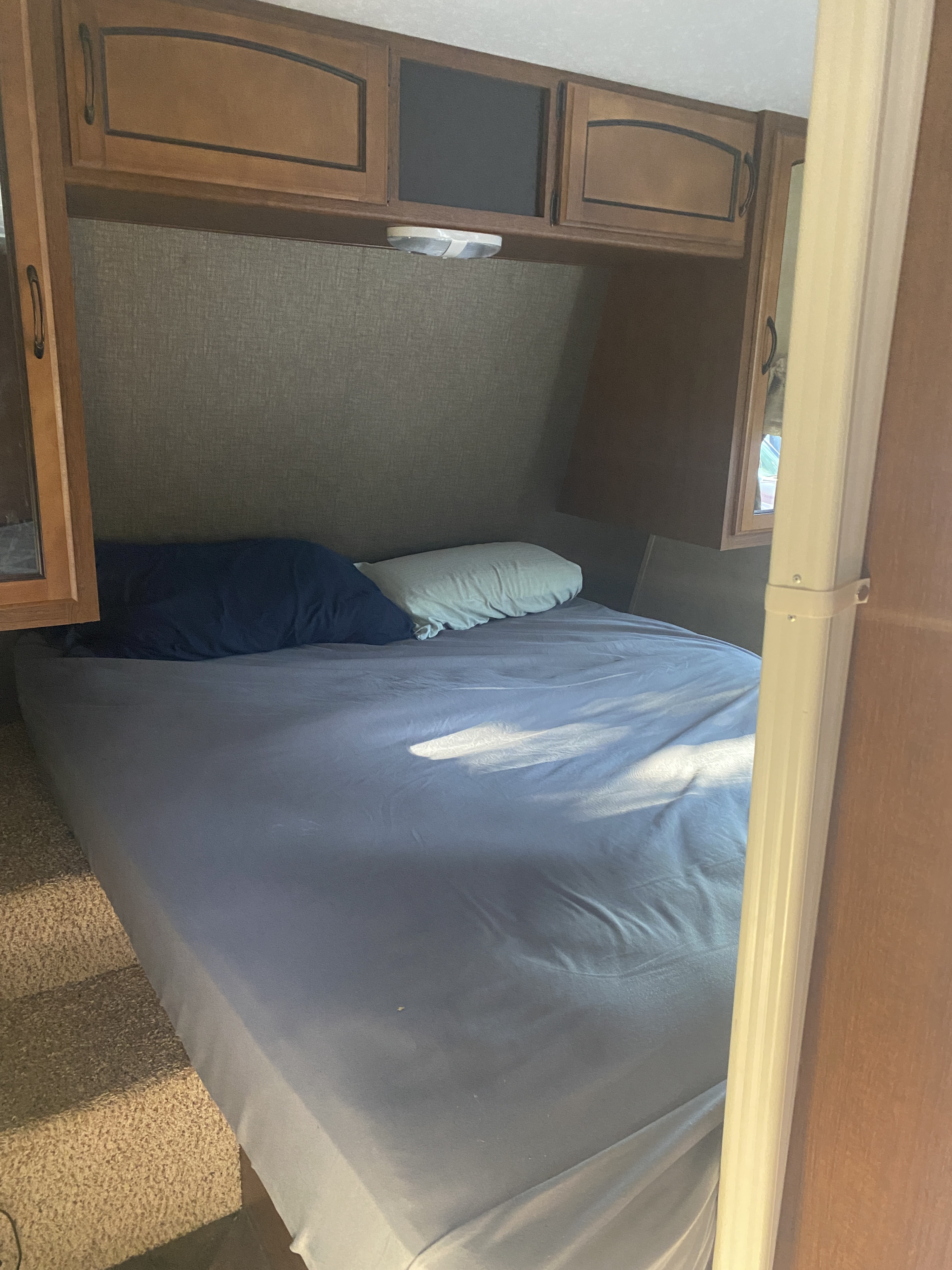 Comfortable bed with overhead cabinets in an RV rental bedroom, perfect for a cozy stay on your trip.. Keystone RV Springdale 2013