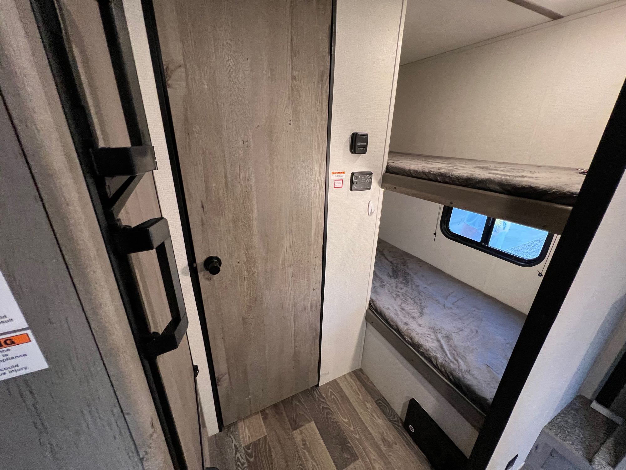 This RV rental's interior shows bunk beds to the right, a door to the left, and wall controls for compact living.. Keystone RV Springdale 2021