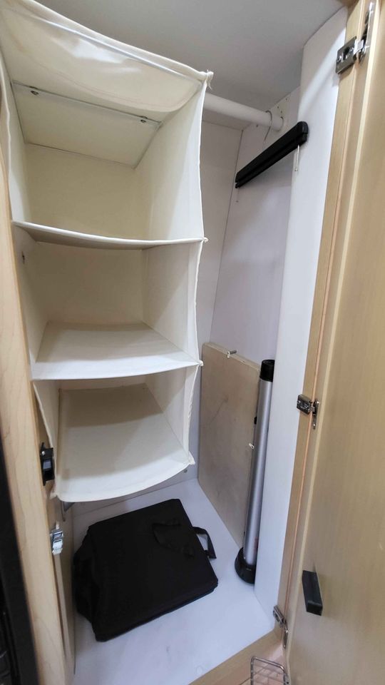 Compact RV rental closet with hanging fabric shelves, clothes rod, and floor storage for essentials.. Mercedes AS NEW SPRINTER 4 BERTH DISCOVERY AUTO TURBO DIESEL 2013