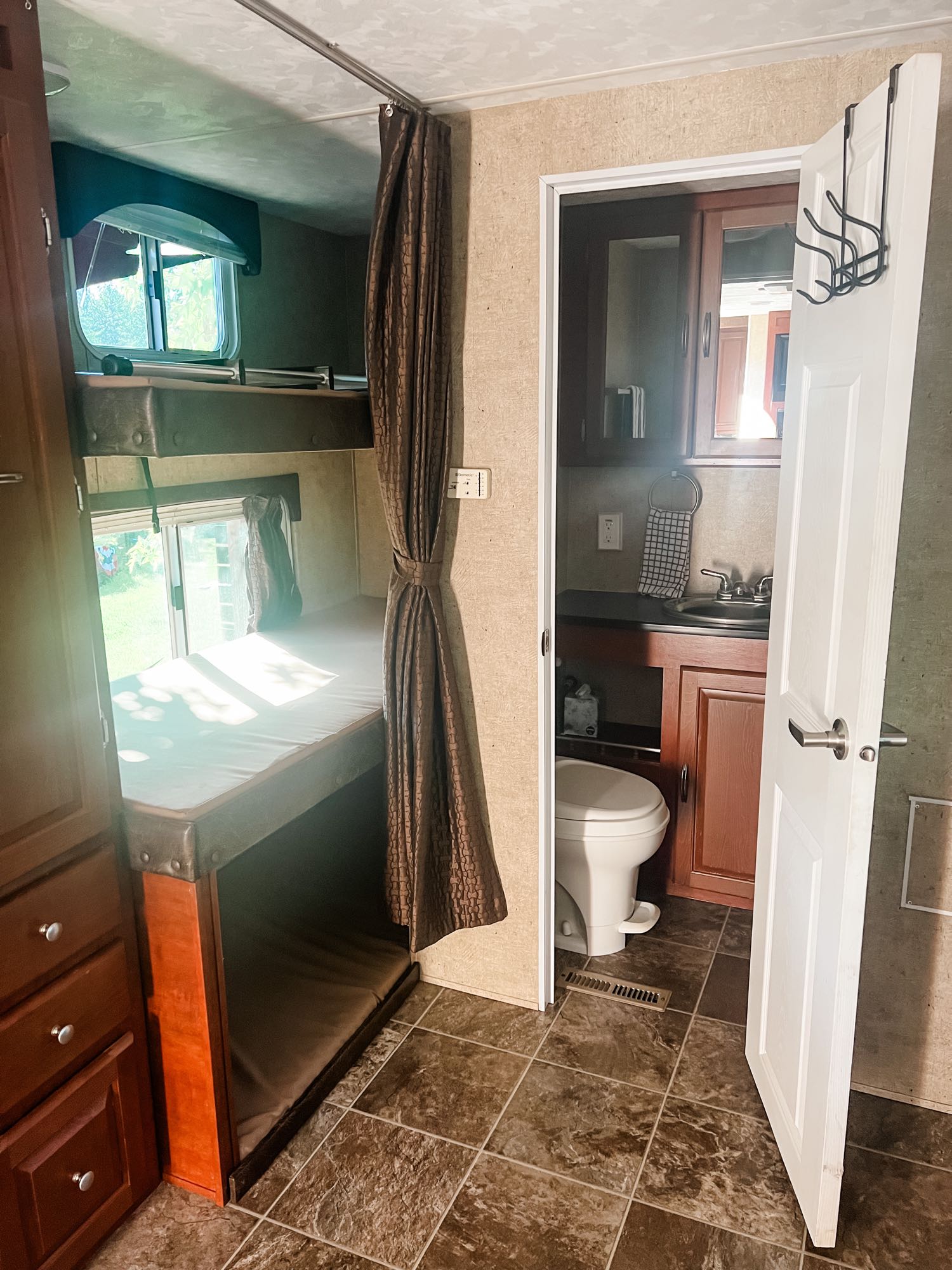 RV rental interior: Bunk beds with a privacy curtain and a compact bathroom featuring a toilet and sink.. Forest River Wildwood 2011