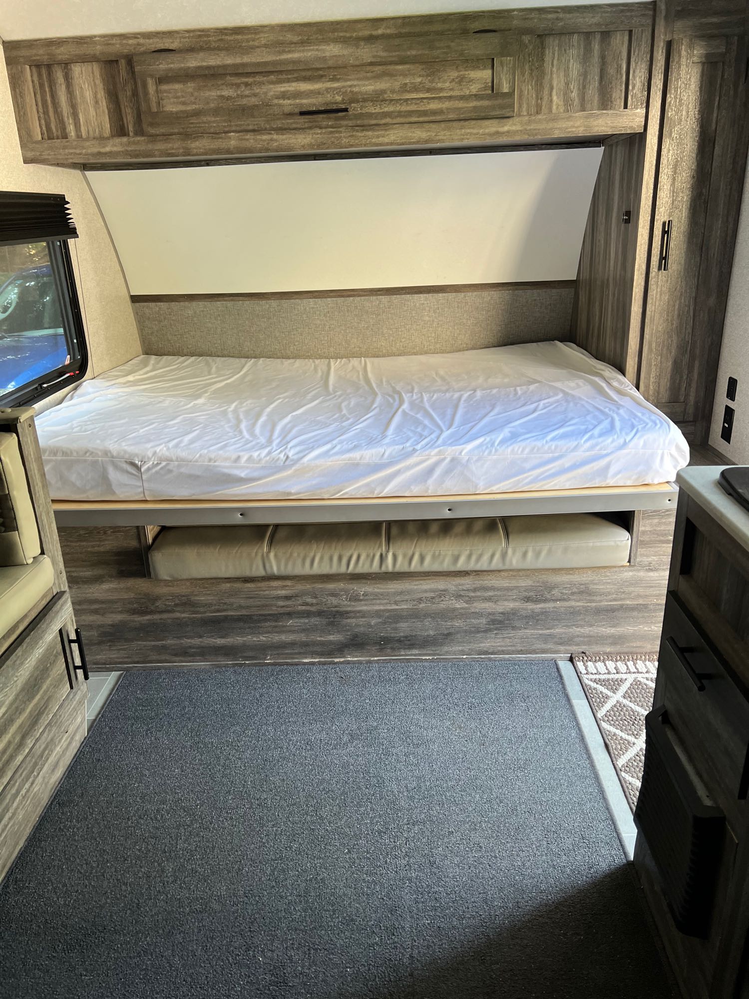 RV rental: View of a compact RV interior with a bed, overhead storage, and a versatile cushioned bench below. Ideal for travel.. Forest River Wildwood FSX 2020