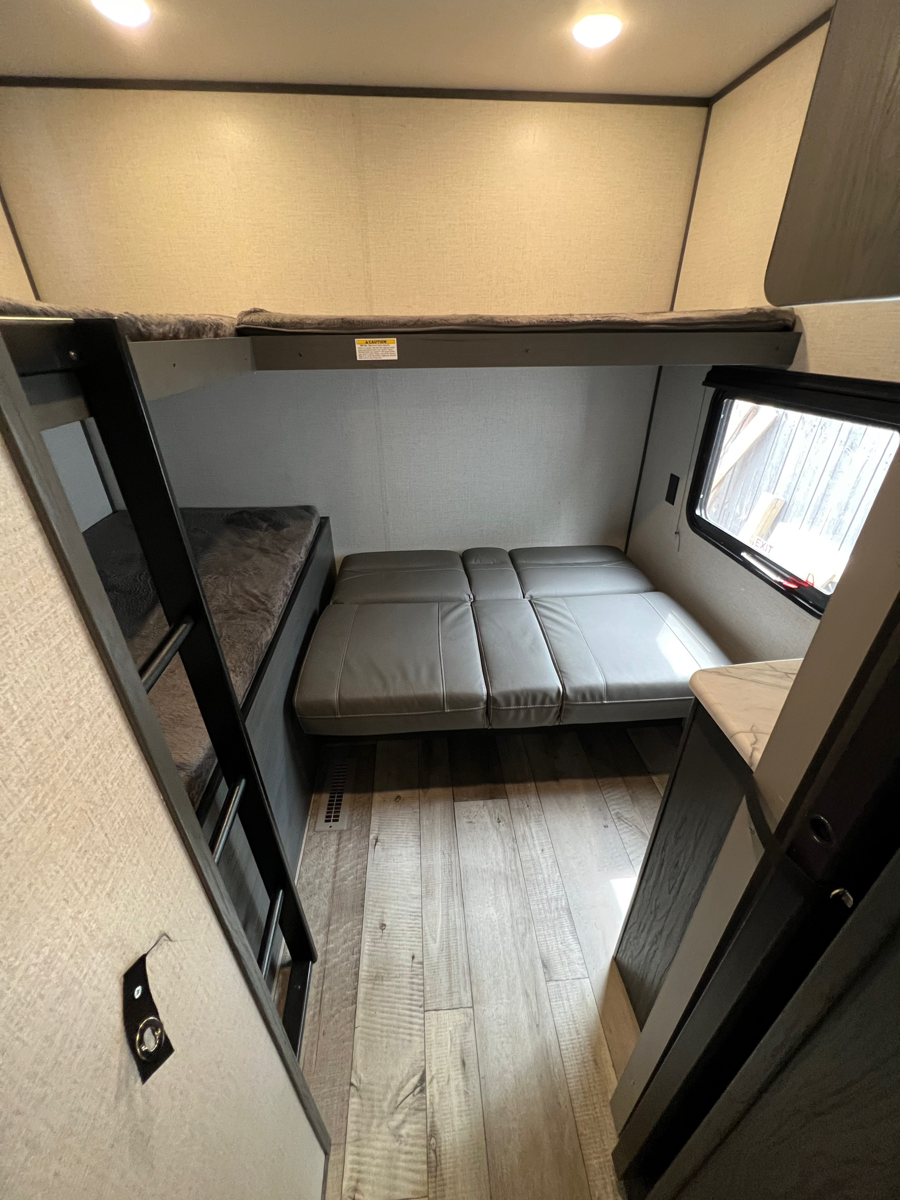 Modern RV rental interior featuring bunk beds, a convertible sofa bed, and wood-look flooring.. Dutchmen Aspen Trail 2022