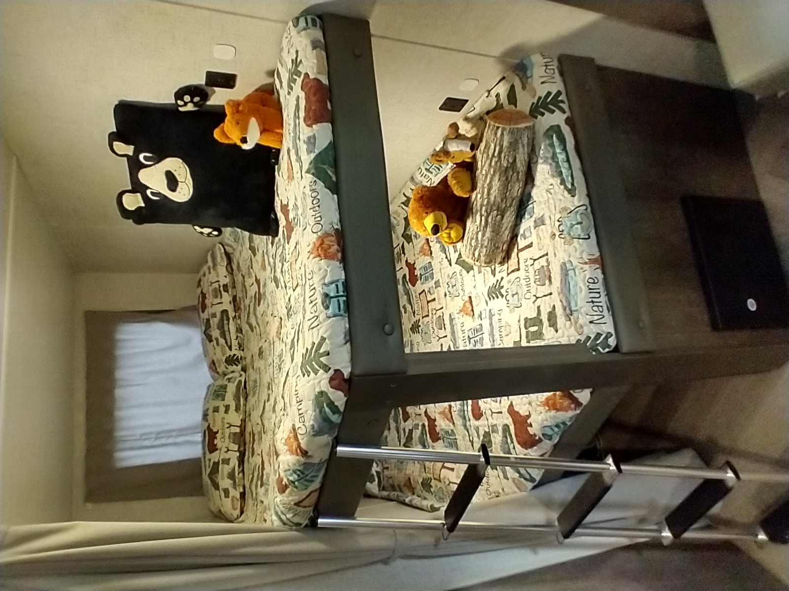 RV rental interior with cozy bunk beds, nature-themed bedding, plush animals, and ladder. Ideal for family camping.. Forest River Wildwood X-Lite 2020