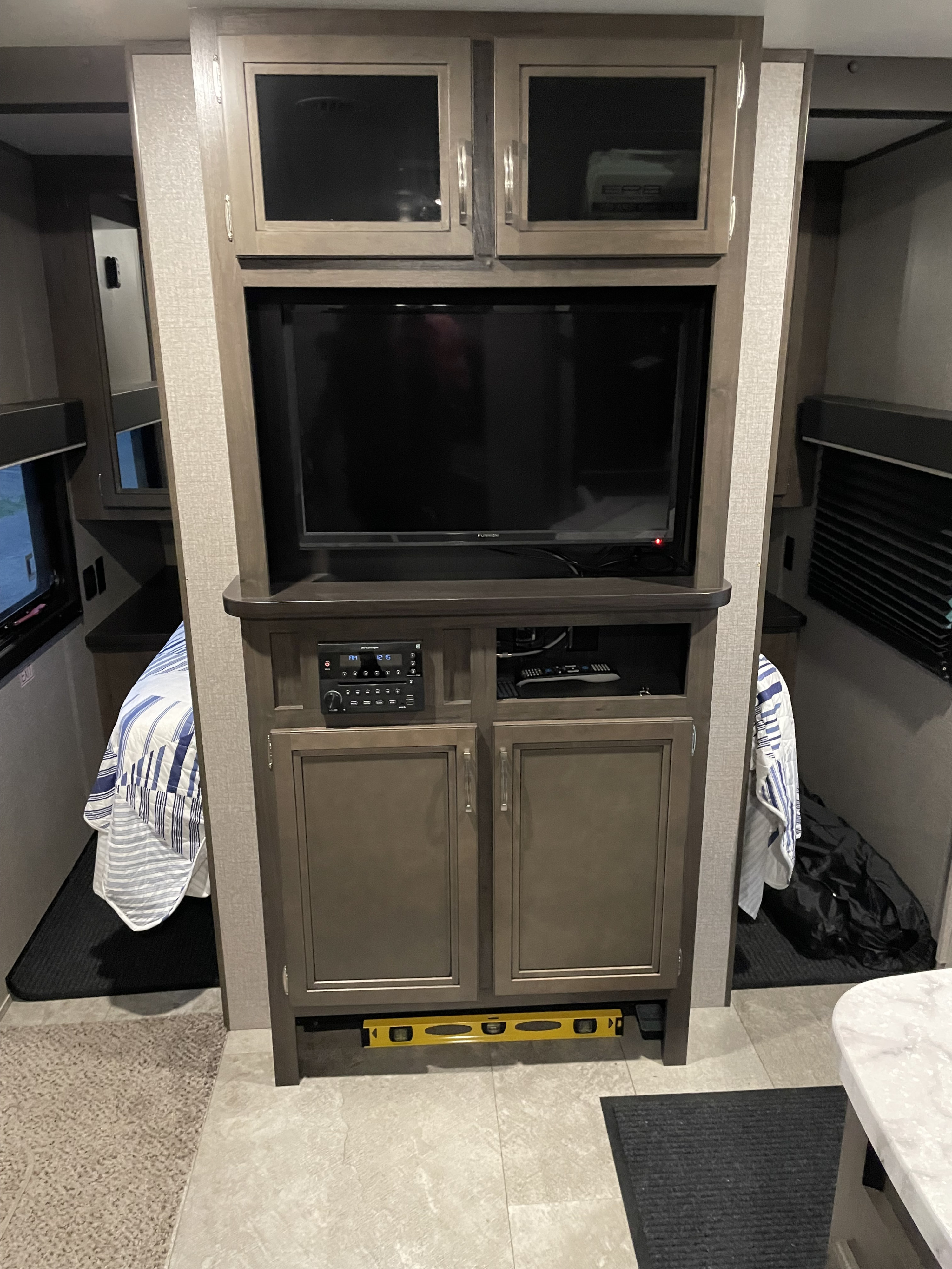 RV rental bunk area featuring a central entertainment system with TVs and audio, flanked by cozy beds and storage.. Jayco Jay Flight SLX 2020
