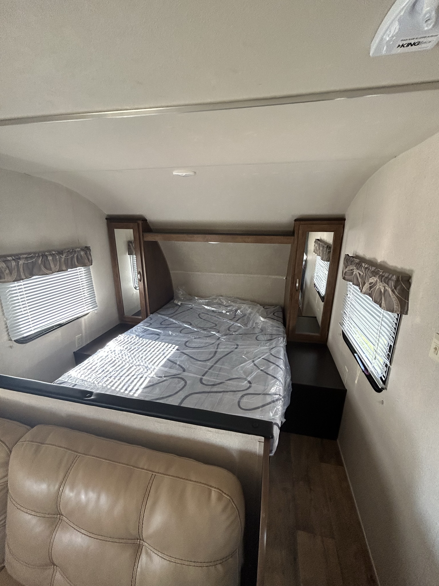 Spacious RV rental interior with bed, windows, and leather couch. Perfect for travel trailer adventures.. Forest River Wildwood X-Lite 2017