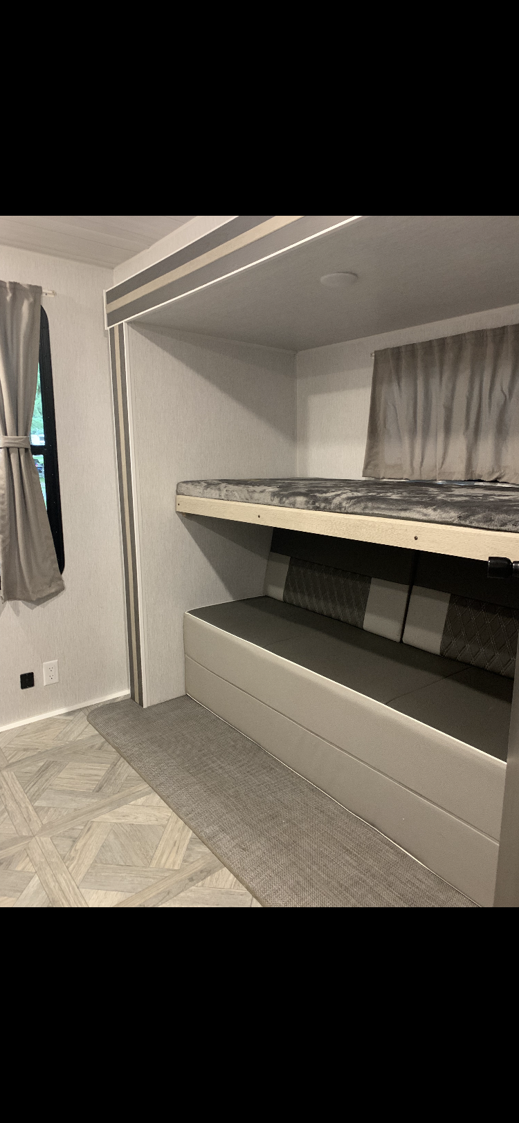 RV rental interior: cozy bunk beds with lower seating, light decor, and floor mat.. Forest River Wildwood FSX Platinum 2023