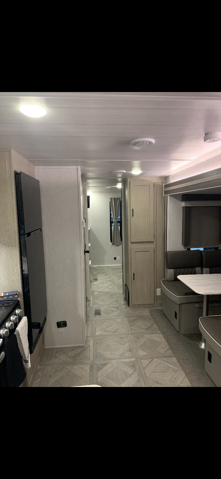 Spacious RV rental interior: kitchen with fridge, dining booth, and hallway. Light-toned cabin with modern fixtures, perfect for travel.. Forest River Wildwood FSX Platinum 2023