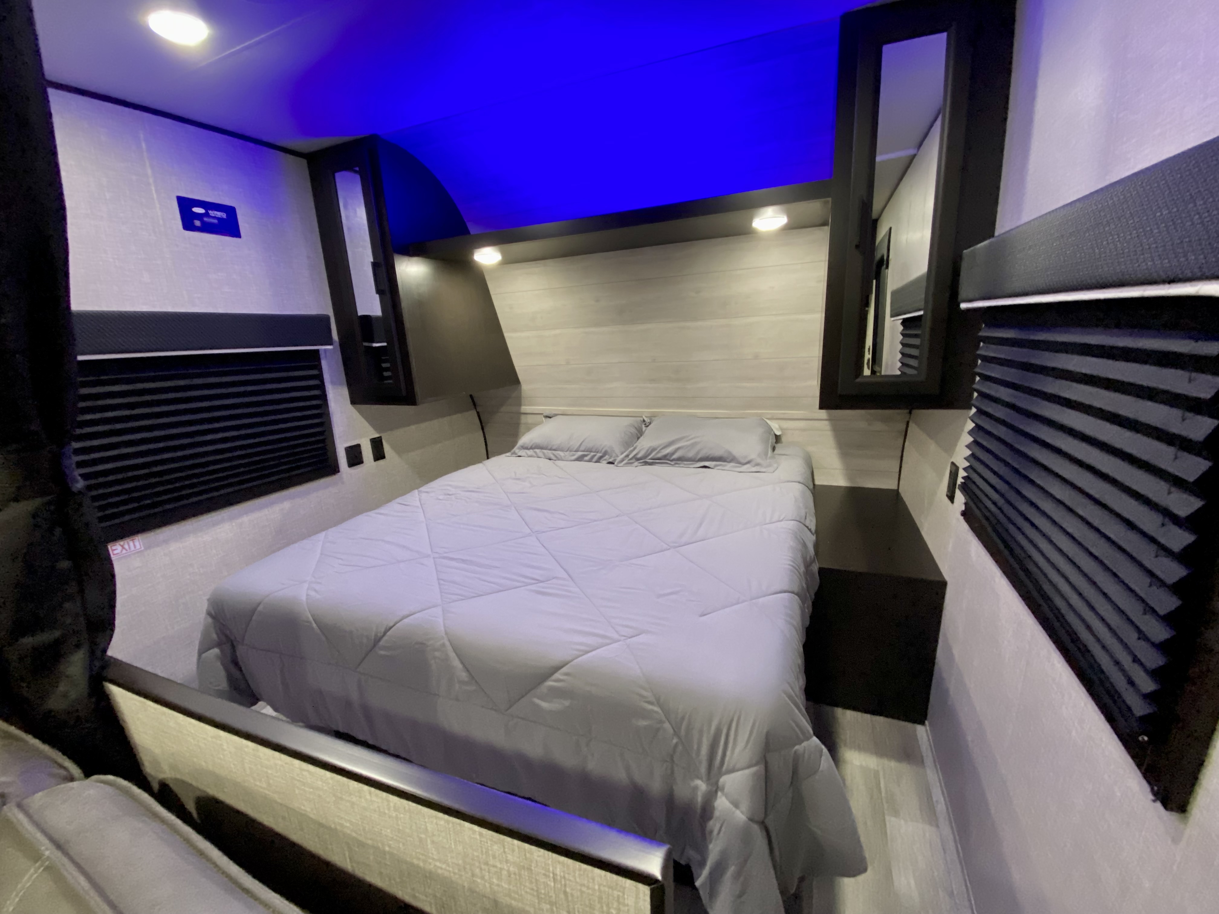 RV rental bedroom interior: featuring a cozy bed, window shades, built-in storage, and blue ambient lighting.. Jayco Jay Flight 2023