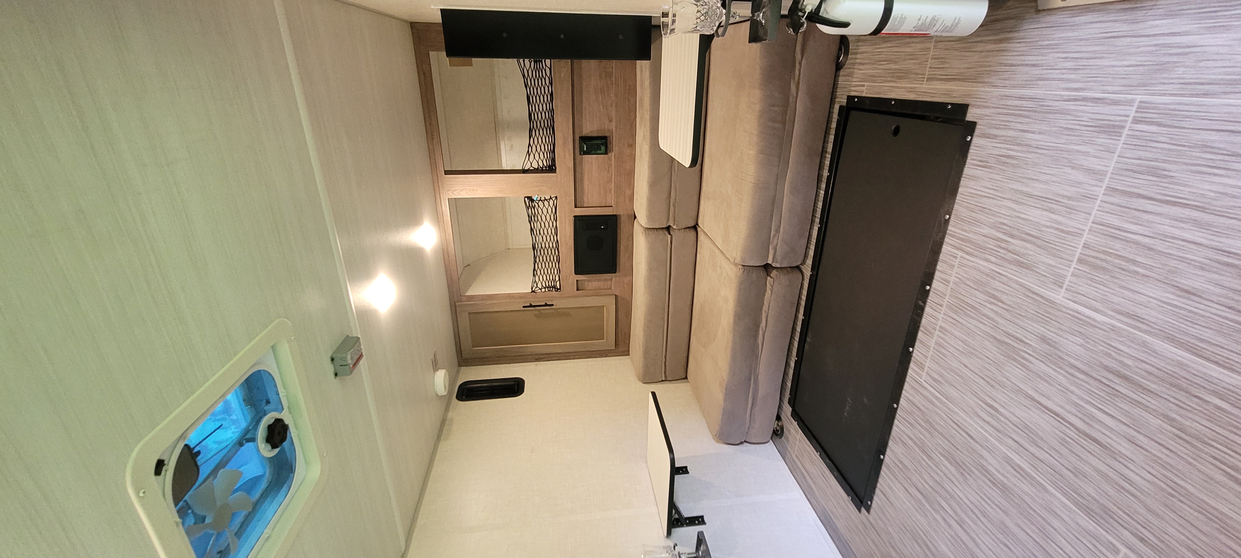 RV rental interior with wood-paneled walls, bunk beds, and a versatile sofa/dinette seating area.. Forest River NoBo 10.6 2022