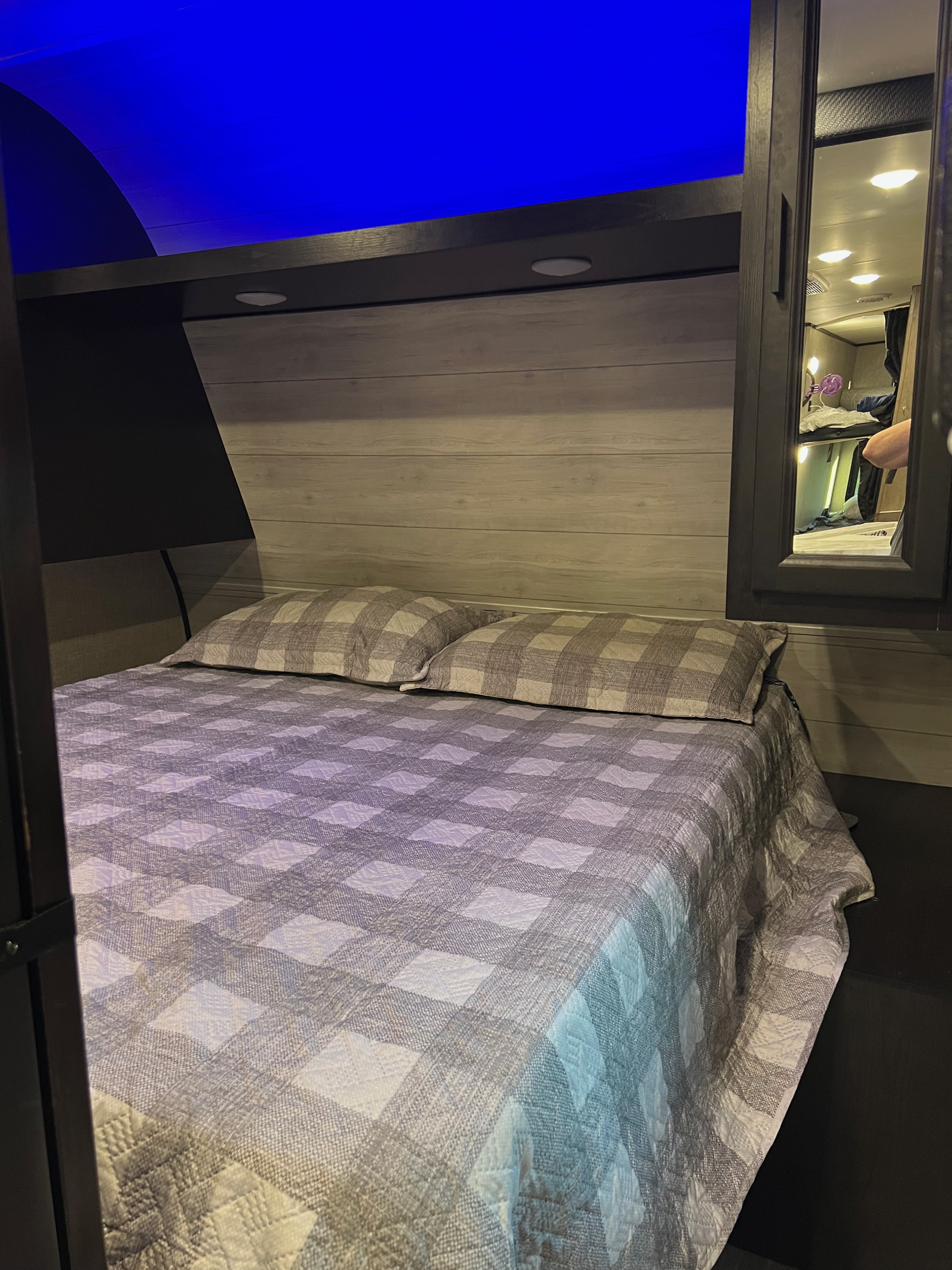 Cozy RV rental bedroom with plaid bedding and ambient blue lighting. A mirror reflects the interior, possibly bunks.. Jayco Jay Flight SLX Rocky Mountain Edition 2022