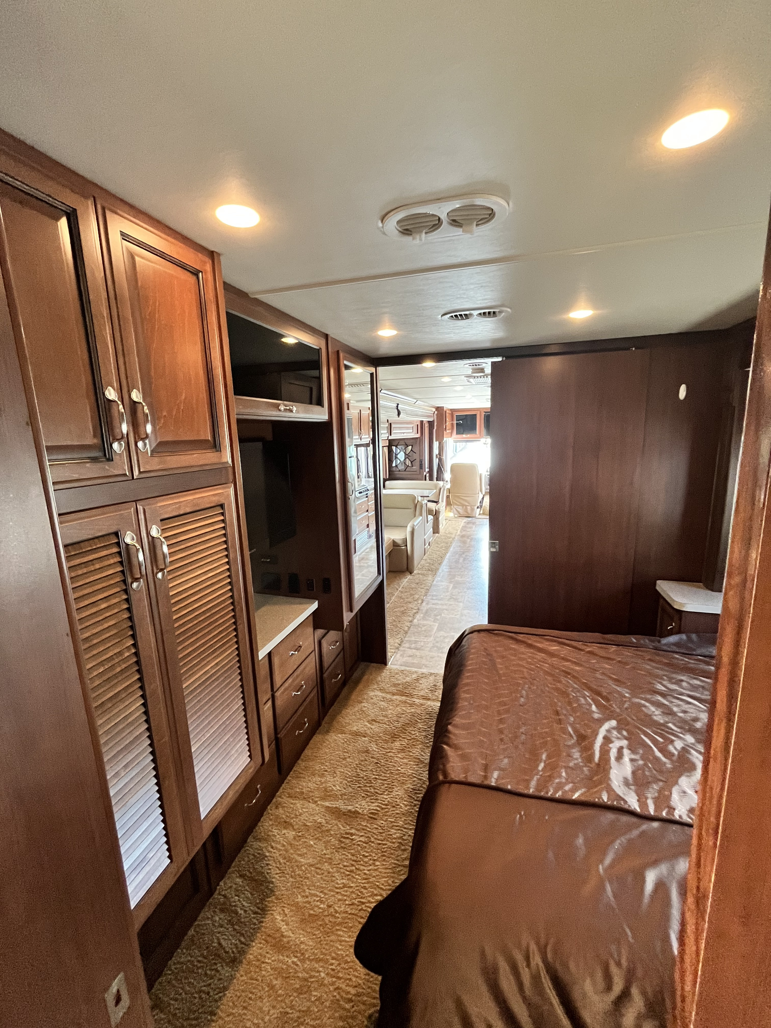 Spacious RV rental interior: View from bedroom showing wood cabinetry, leading to a bright living area.. Fleetwood Bounder 2013