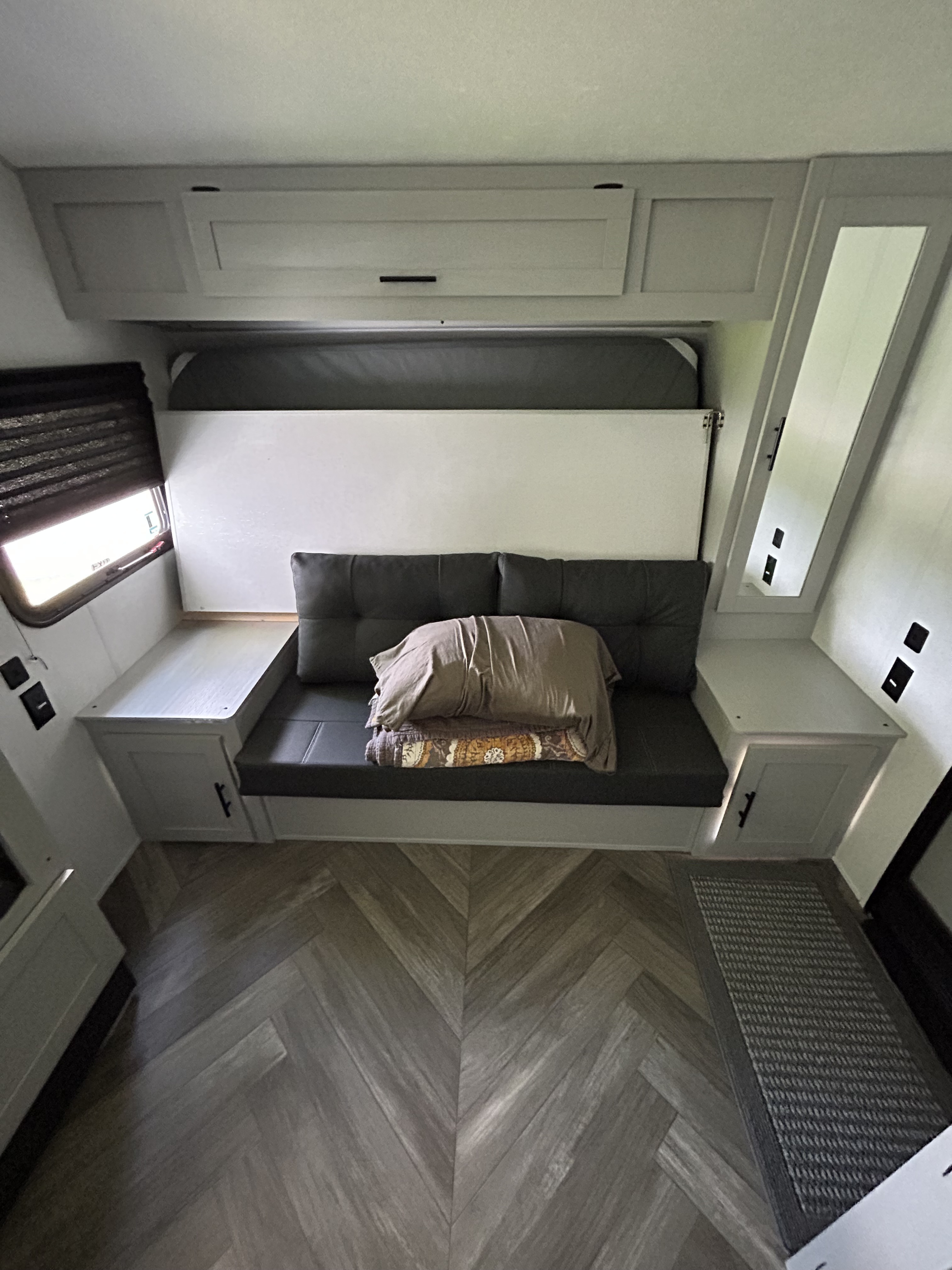 Compact RV rental interior featuring a versatile sofa that converts to a bed, overhead storage, and herringbone floor.. Forest River Salem 2022