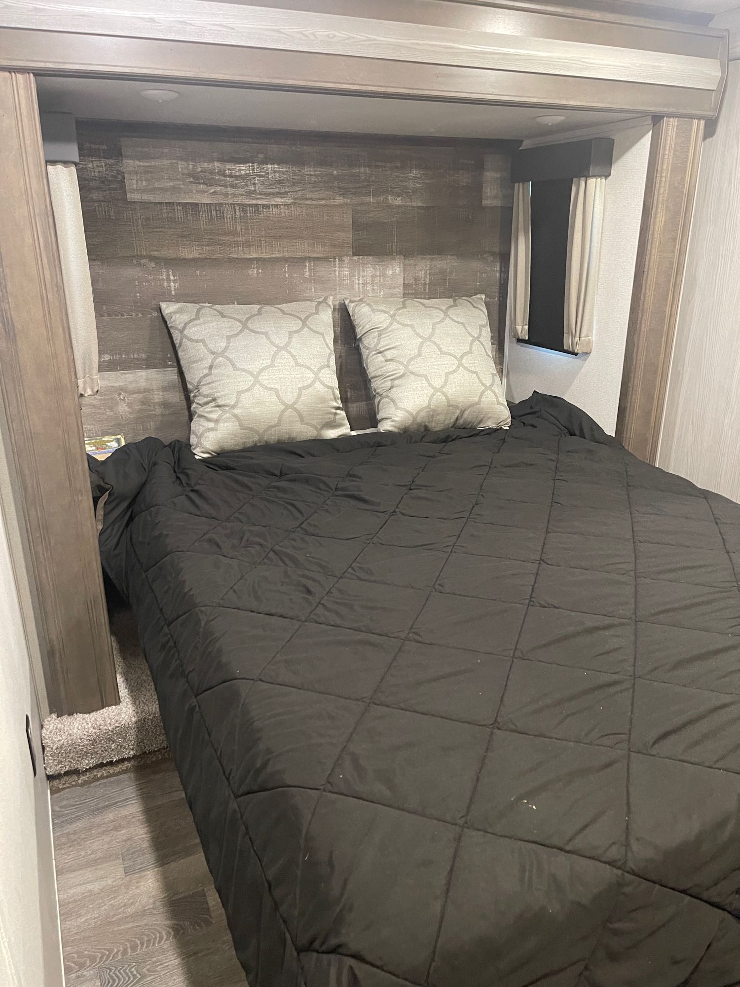 RV rental bedroom: A cozy, compact space with a comfortable bed, wood headboard, and curtained windows.. Keystone RV Montana High Country 2020