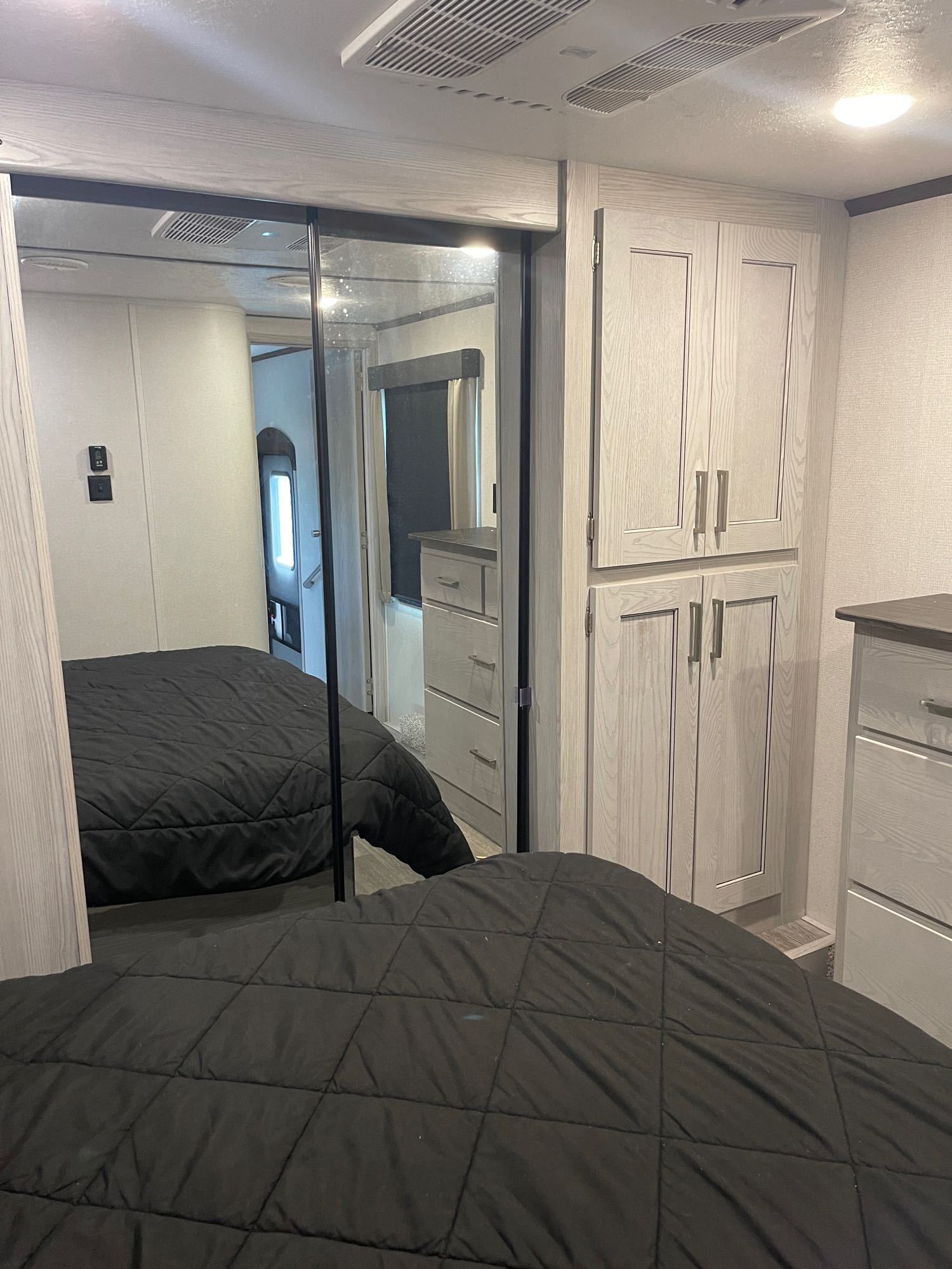 Modern RV rental bedroom with black bed, mirrored closet, and ample storage for comfortable travel.. Keystone RV Montana High Country 2020