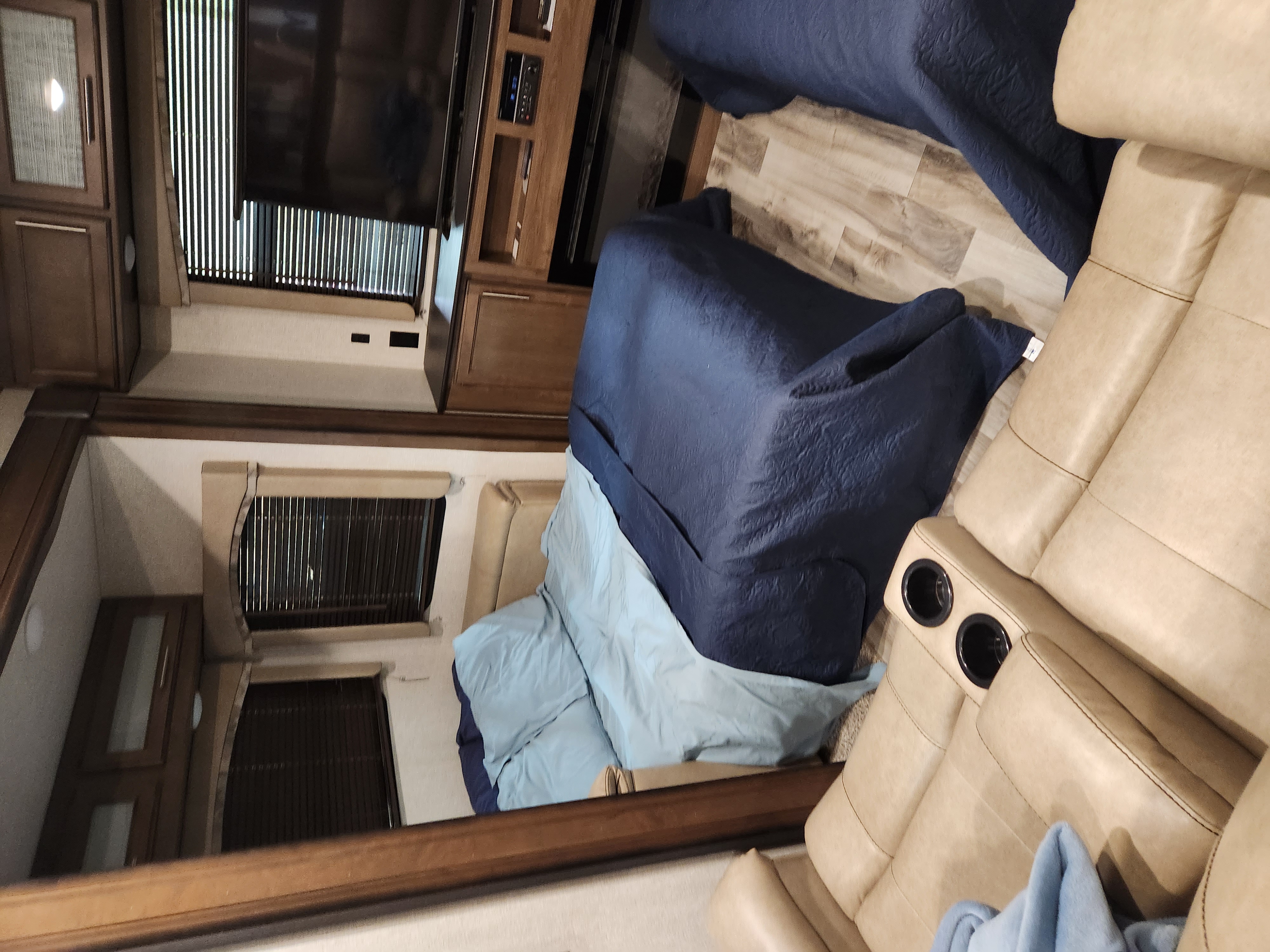 Inside a comfy rv rental, showing the entertainment area with TV, beds, and recliners with cup holders.. Keystone RV Cougar 2018