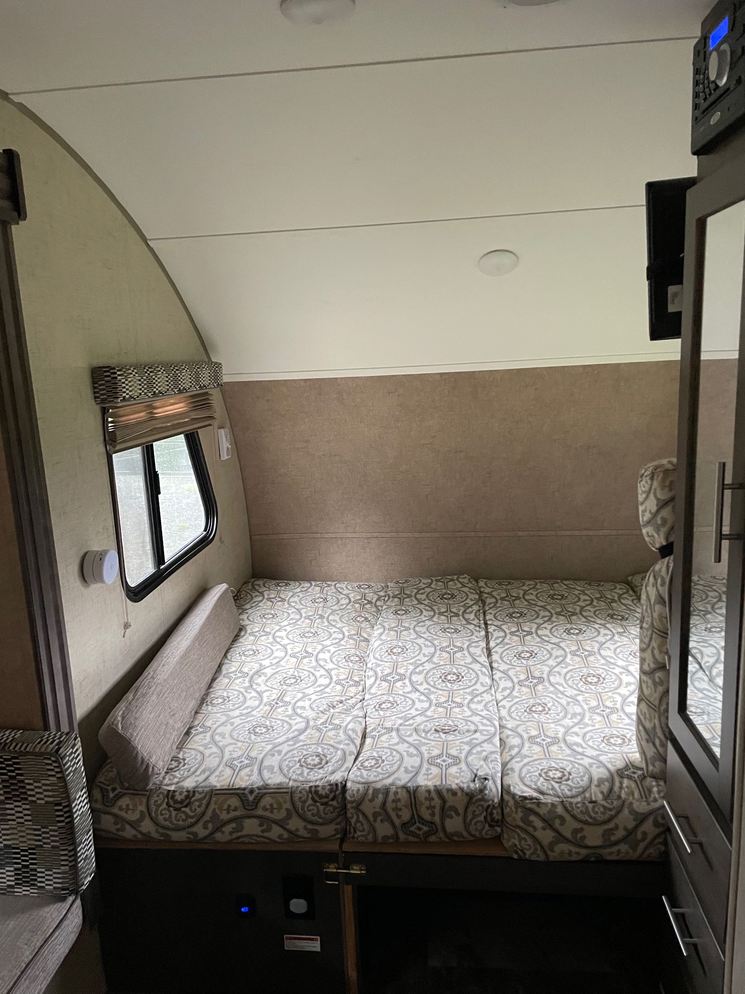Compact RV rental interior featuring a patterned bed/sleeping area, perfect for travel. Window and storage visible.. R-Pod R-Pod Trailer 2017
