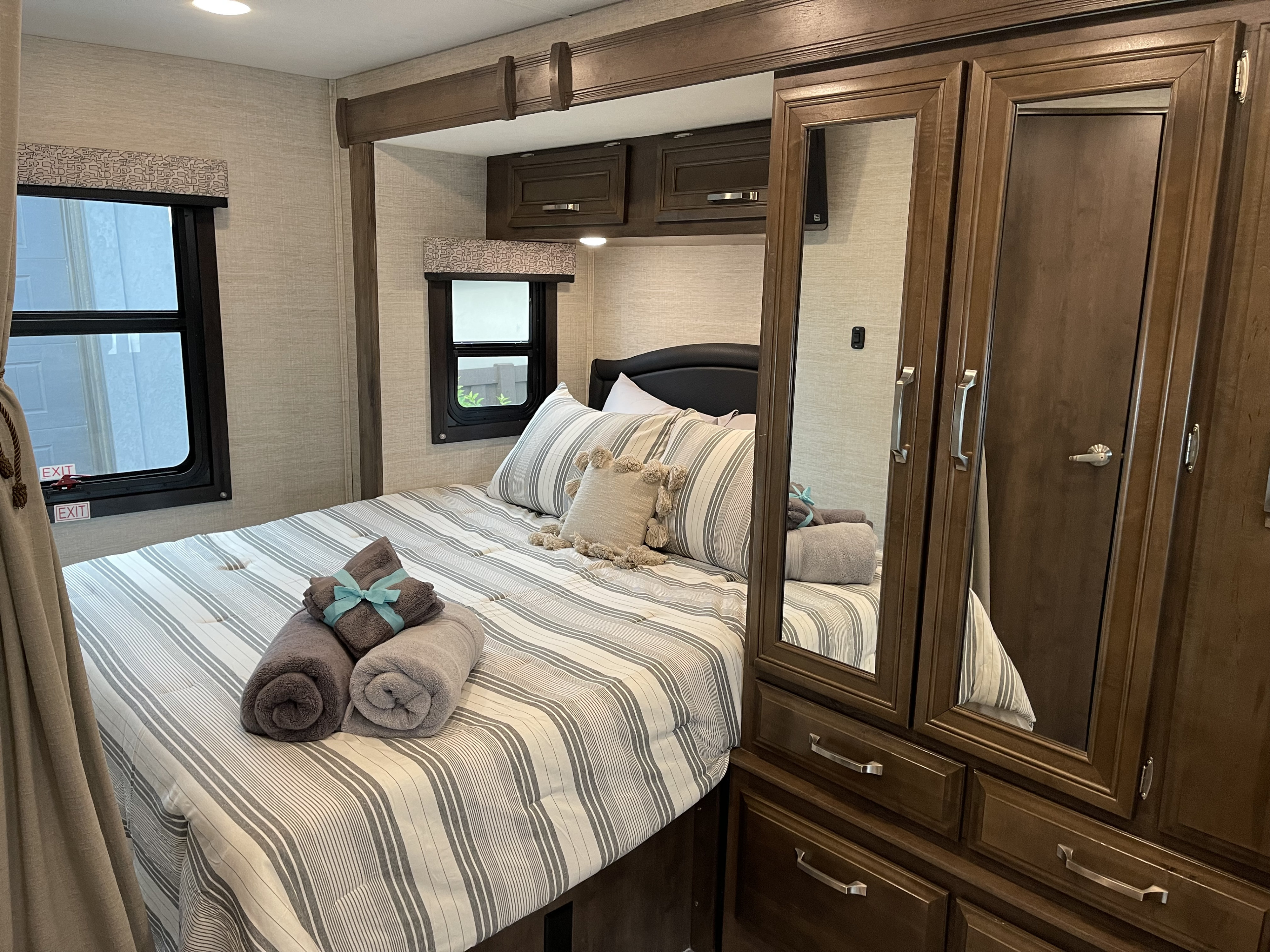 RV rental bedroom with bed, striped linens, and mirrored closet, offering comfortable overnight stays.. Jayco Melbourne 2022