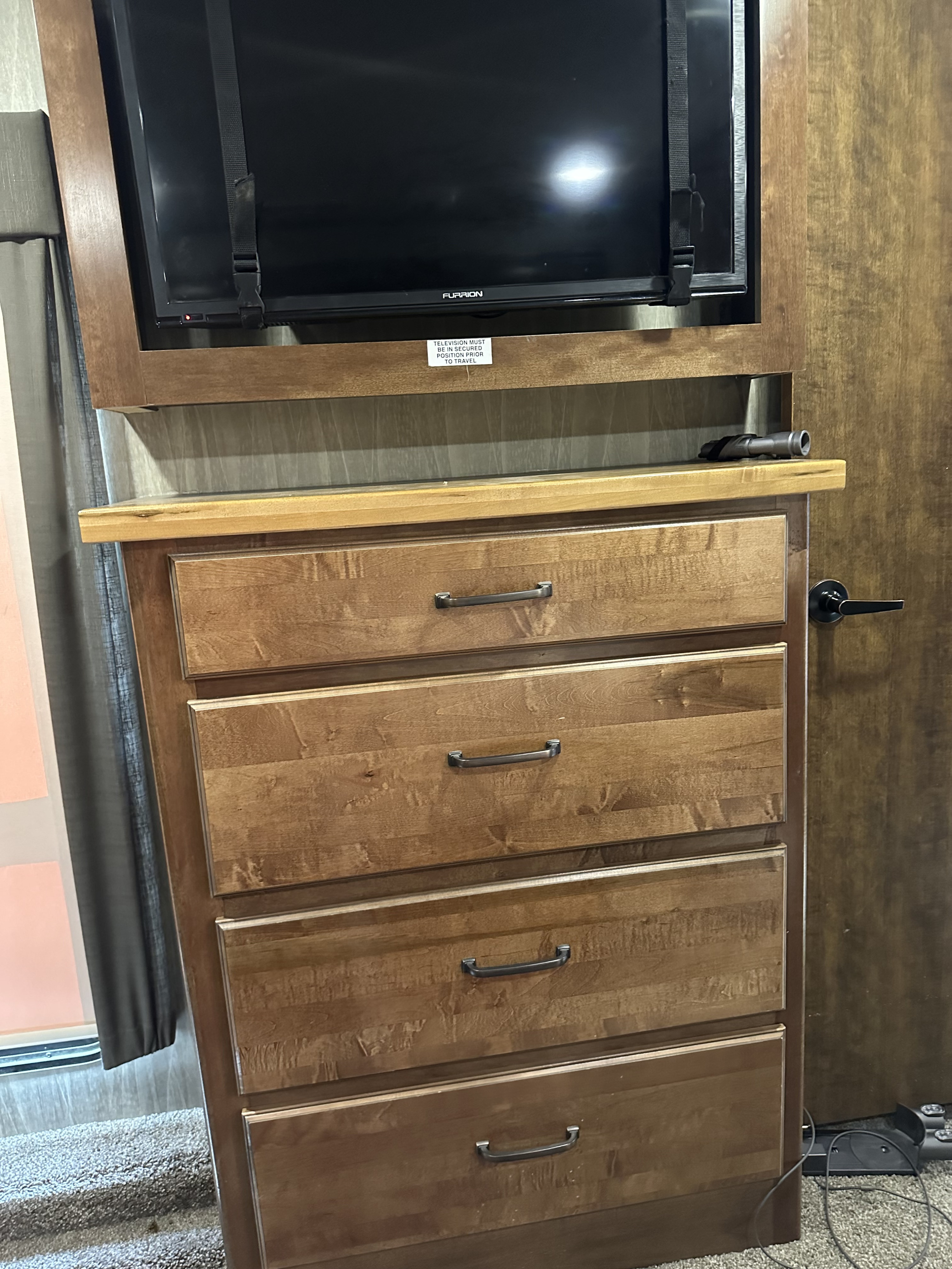RV rental: Secure TV over wood dresser with drawers. A visible warning sticker reminds to secure TV for travel.. Heartland RVs Big Country 2018