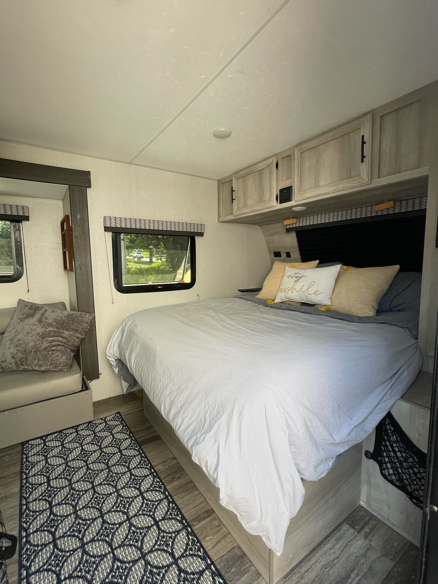 Spacious RV rental bedroom with a plush bed, "stay awhile" pillow, and sitting area. Ideal for your next journey.. KZ Escape 2021